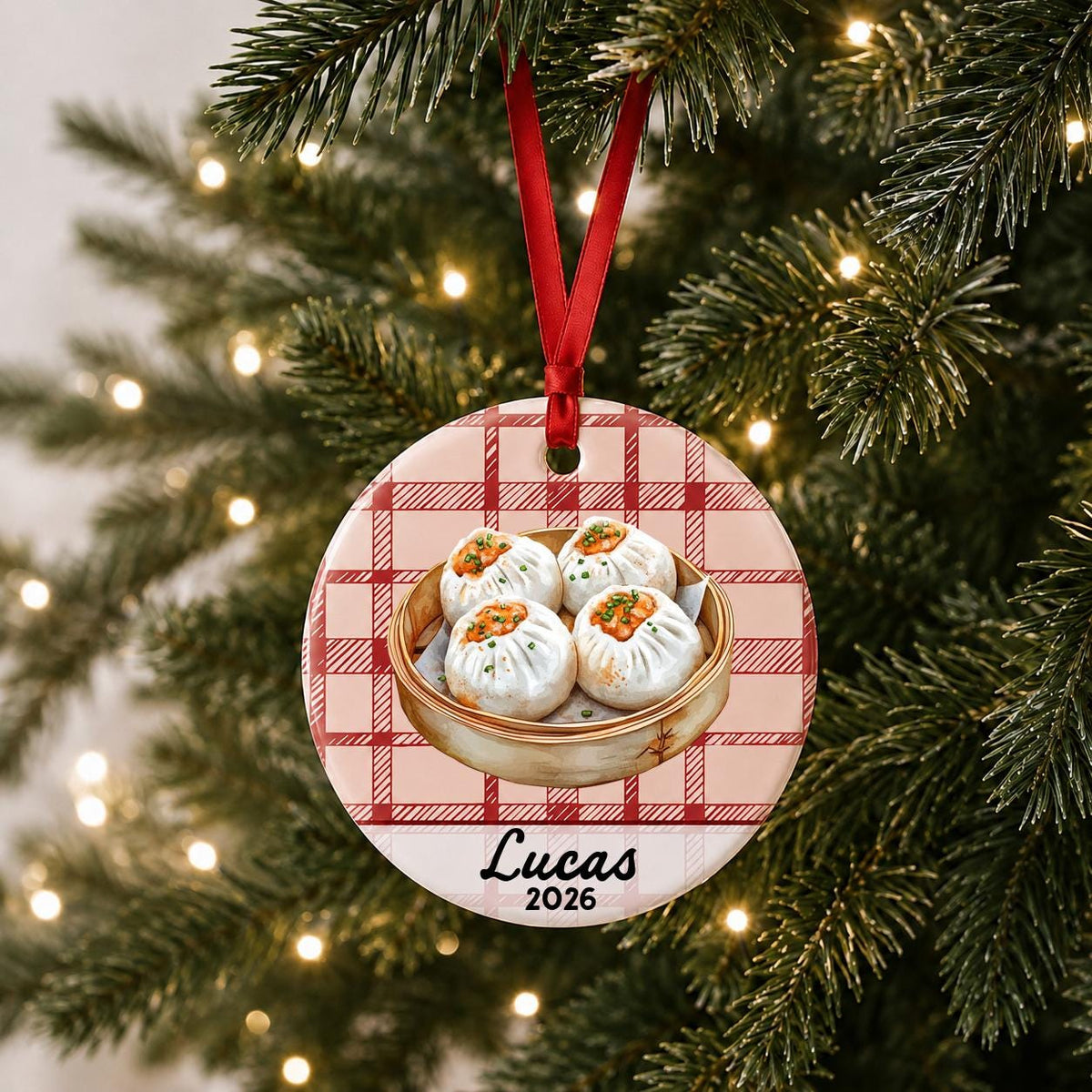 Personalized shumai ceramic ornament with name and year on red plaid hanging on a lit Christmas tree