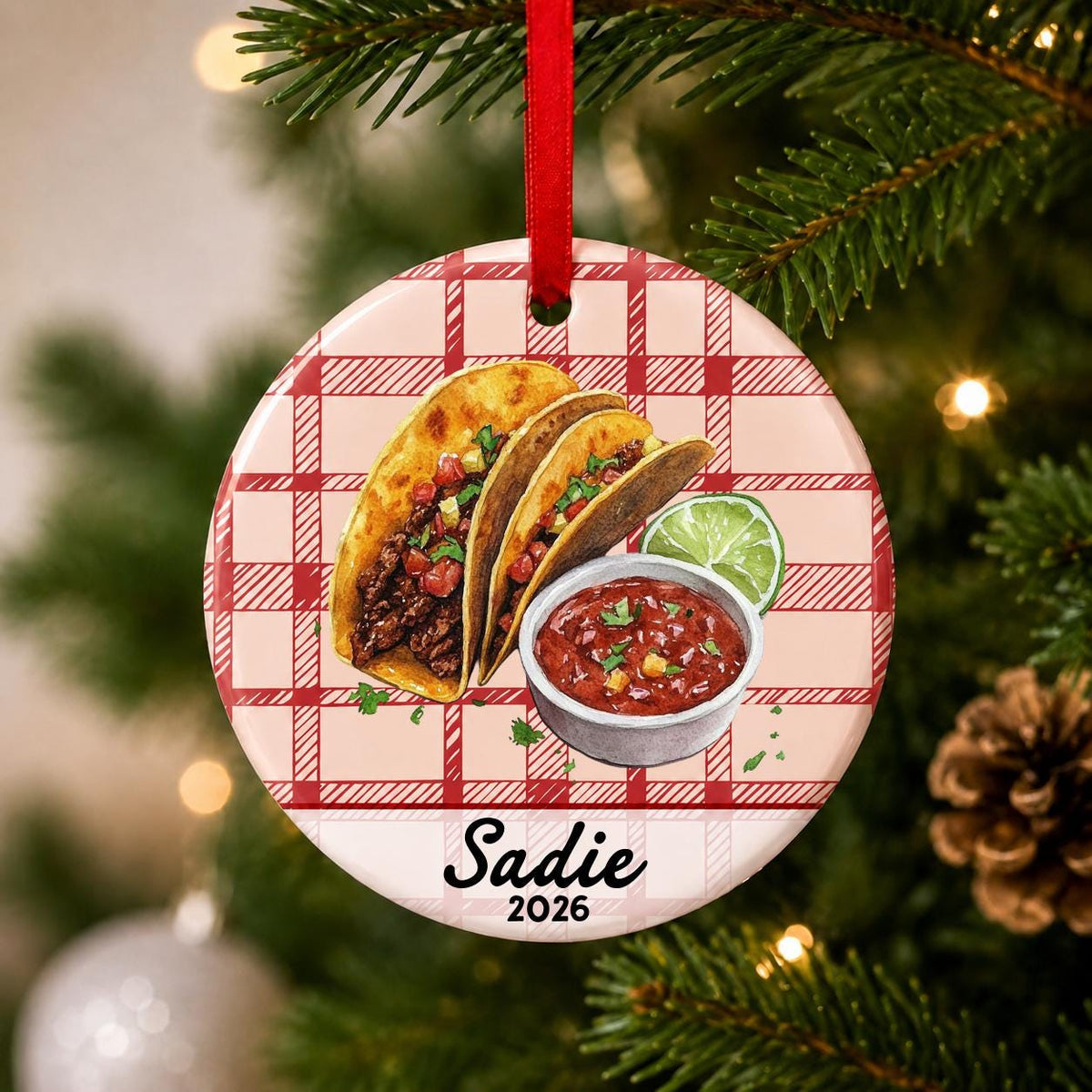 Close-up of the personalized taco ceramic ornament with name and year on red plaid hanging on a Christmas tree
