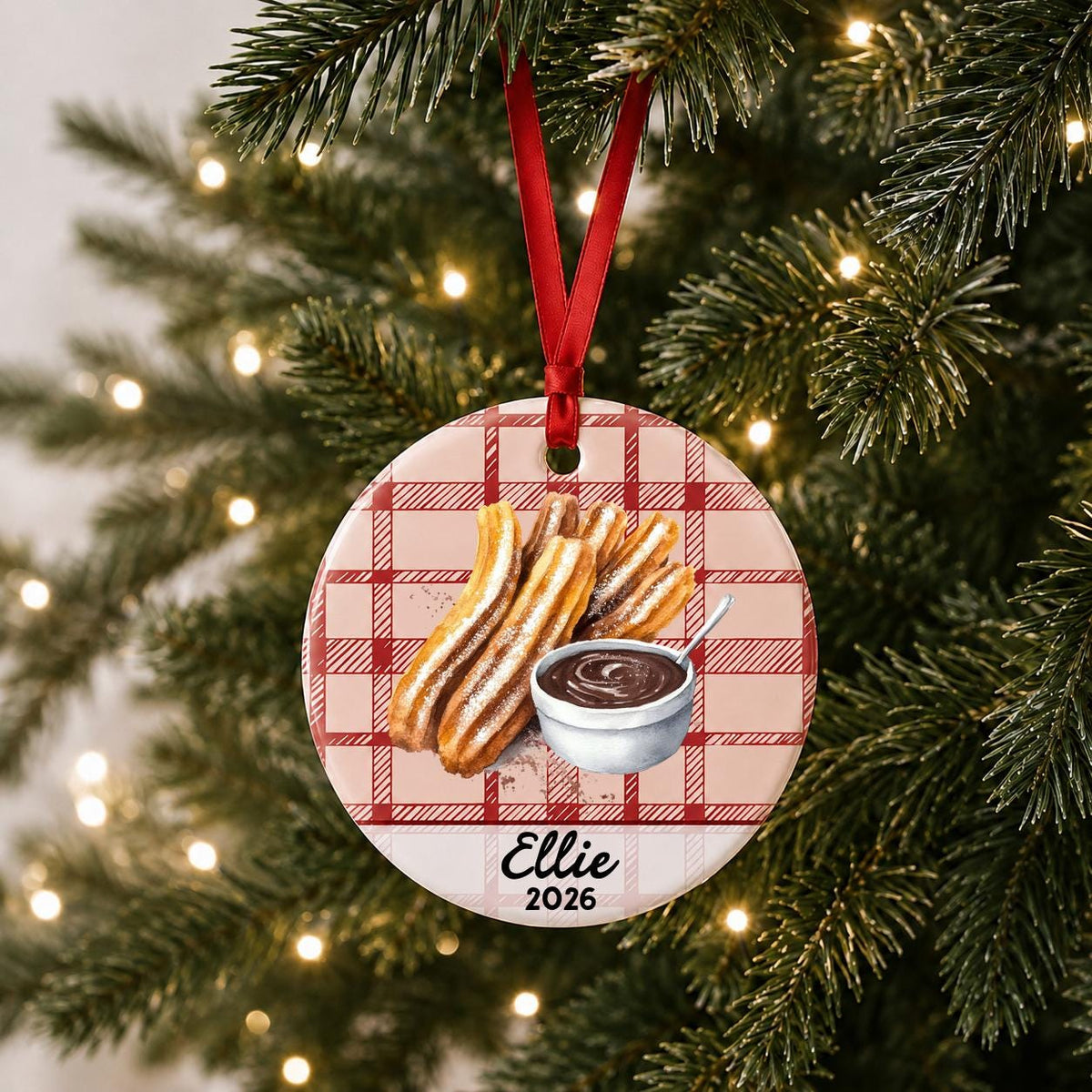 Personalized churro ceramic ornament with name and year on red plaid hanging on a lit Christmas tree