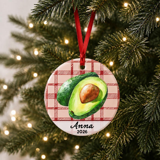 Personalized avocado ceramic ornament with name and year on red plaid hanging on a lit Christmas tree