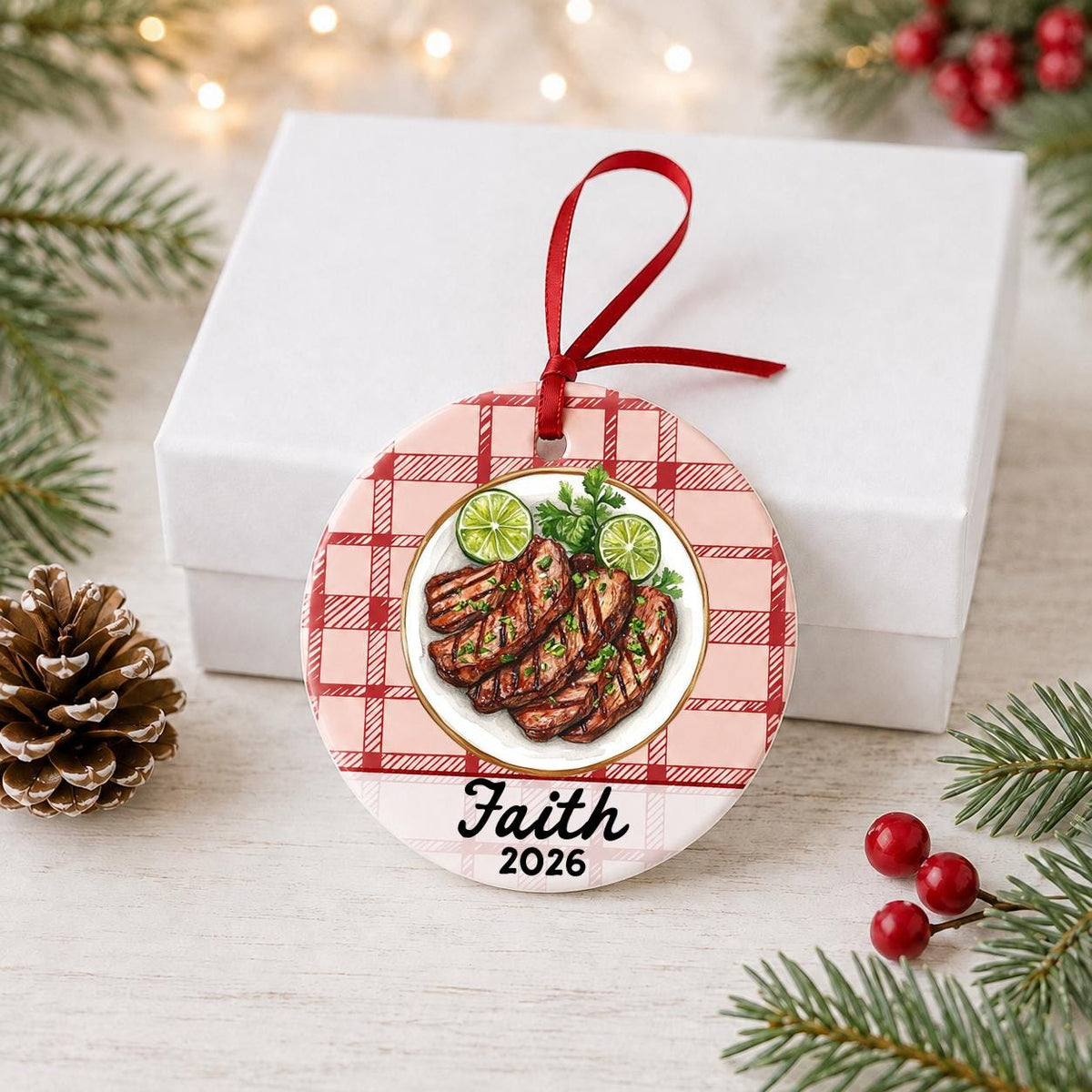 Personalized carne asada ceramic ornament with name and year on red plaid in front of a white gift box with pinecones and red berries
