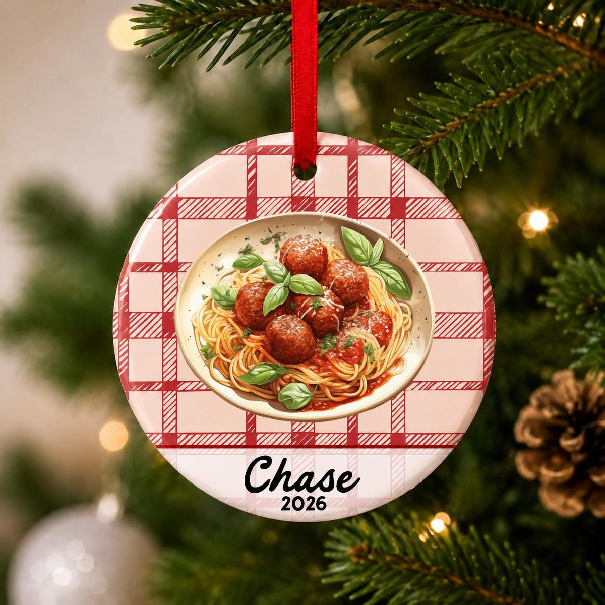 Close-up of the personalized spaghetti and meatballs ceramic ornament with name and year on red plaid hanging on a Christmas tree
