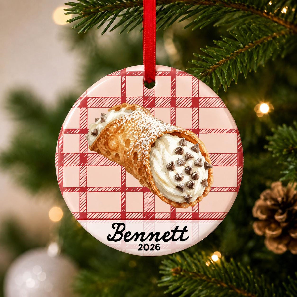 Close-up of the personalized cannoli ceramic ornament with name and year on red plaid hanging on a Christmas tree