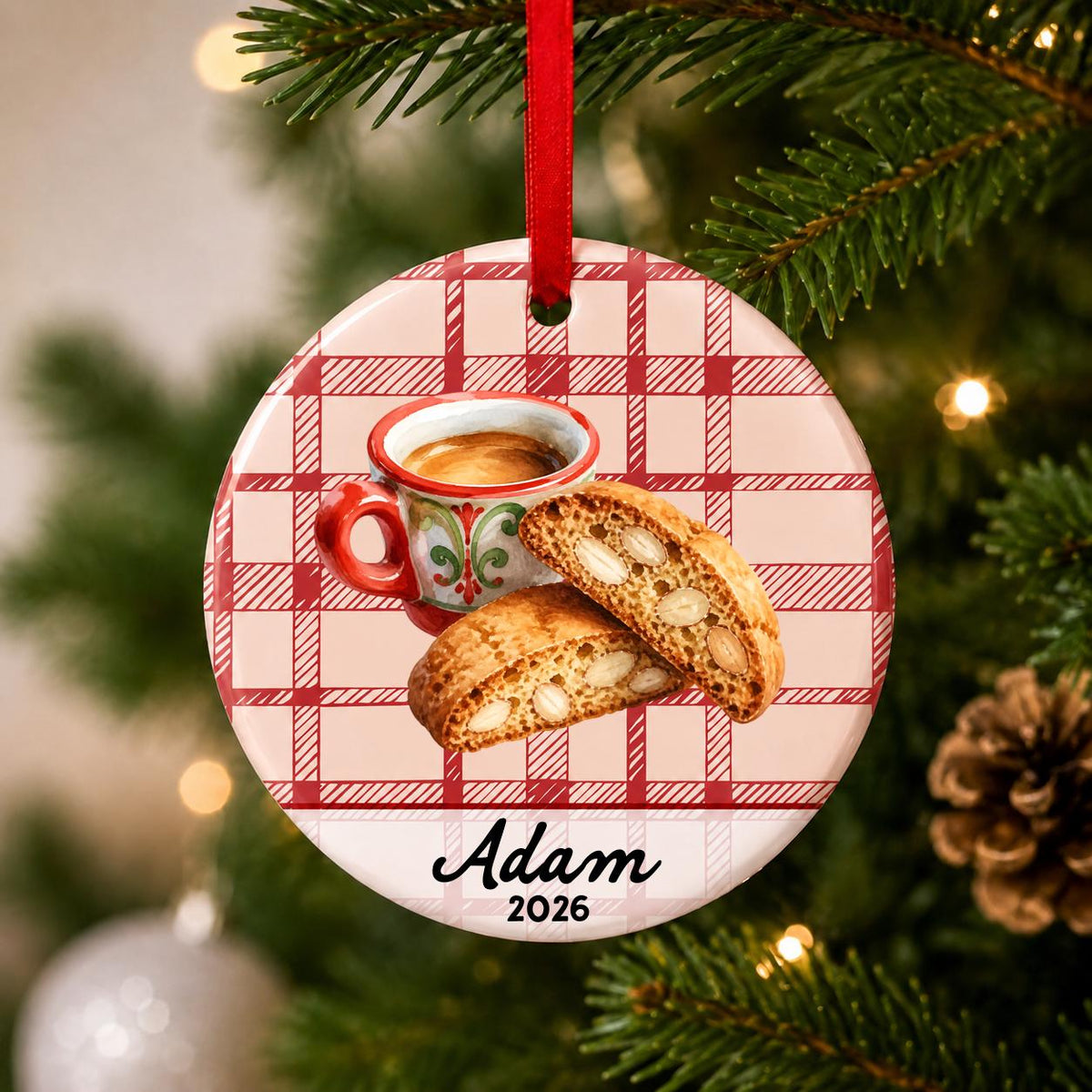 Close-up of the personalized espresso and biscotti ceramic ornament with name and year on red plaid hanging on a Christmas tree