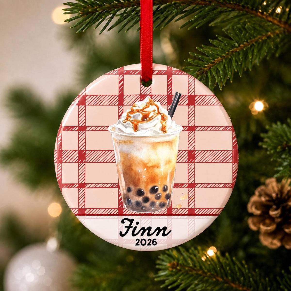 Close-up of the personalized brown sugar boba ceramic ornament with name and year on red plaid hanging on a Christmas tree
