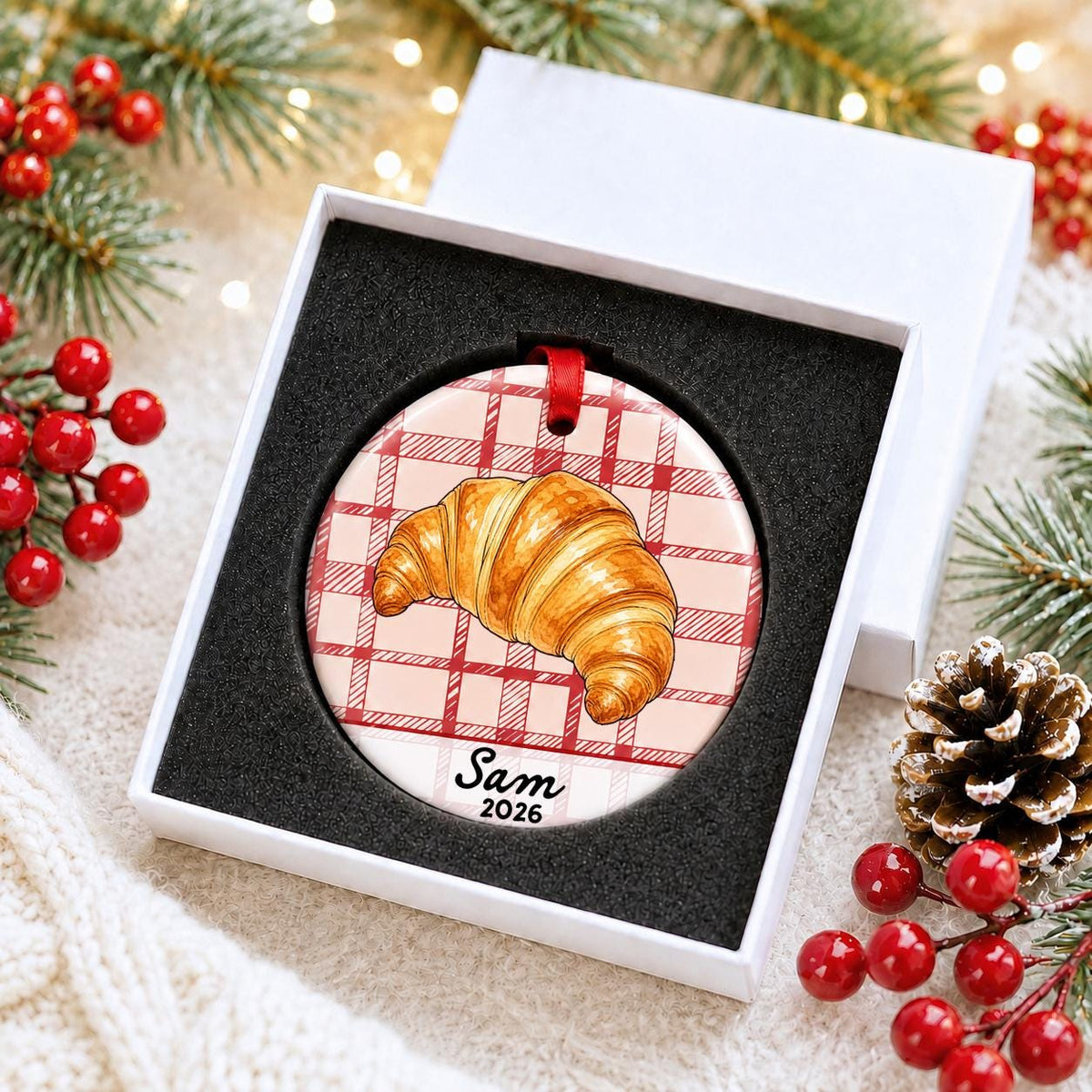 Personalized croissant ceramic ornament with name and year on red plaid in a white gift box with protective foam