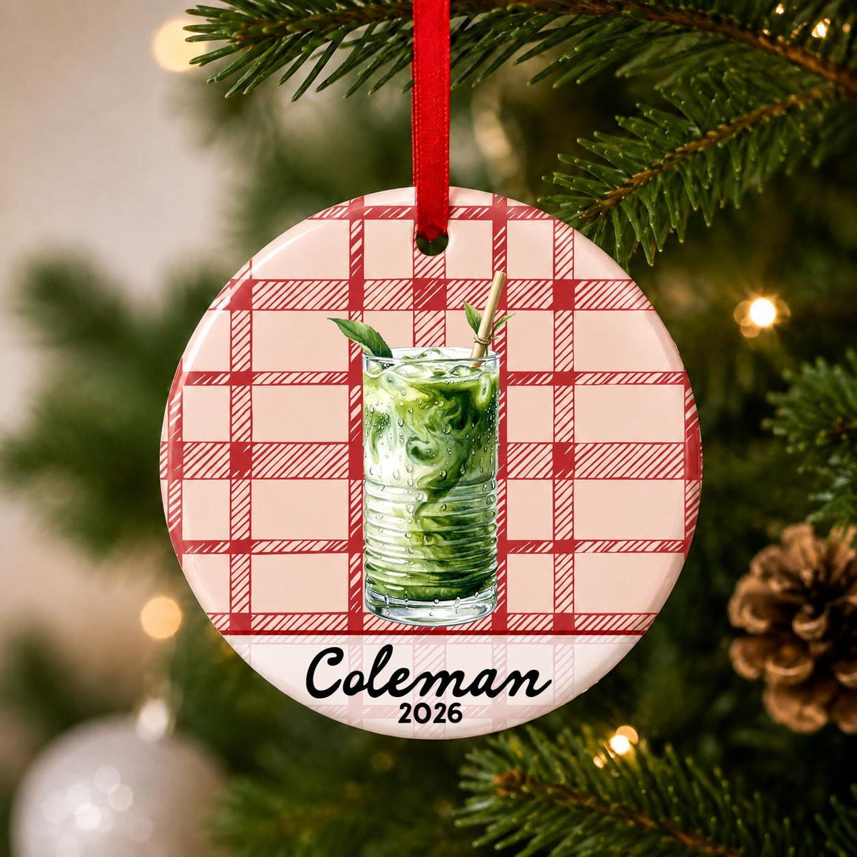 Close-up of the personalized iced matcha ceramic ornament with name and year on red plaid hanging on a Christmas tree