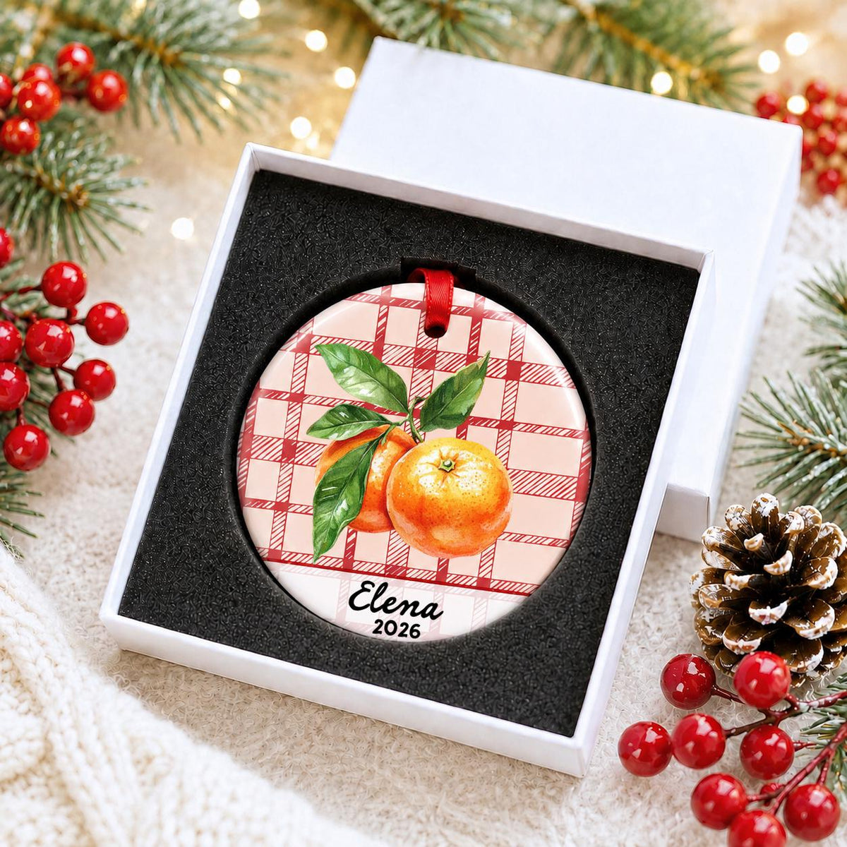 Personalized clementine ceramic ornament with name and year on red plaid in a white gift box with protective foam