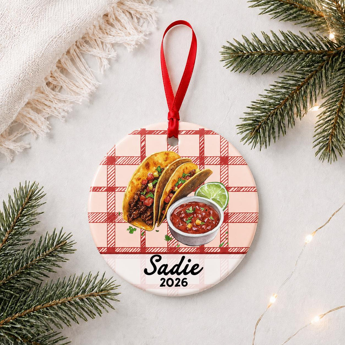 Personalized taco ceramic ornament with name and year on red plaid styled with pine branches on a soft white background
