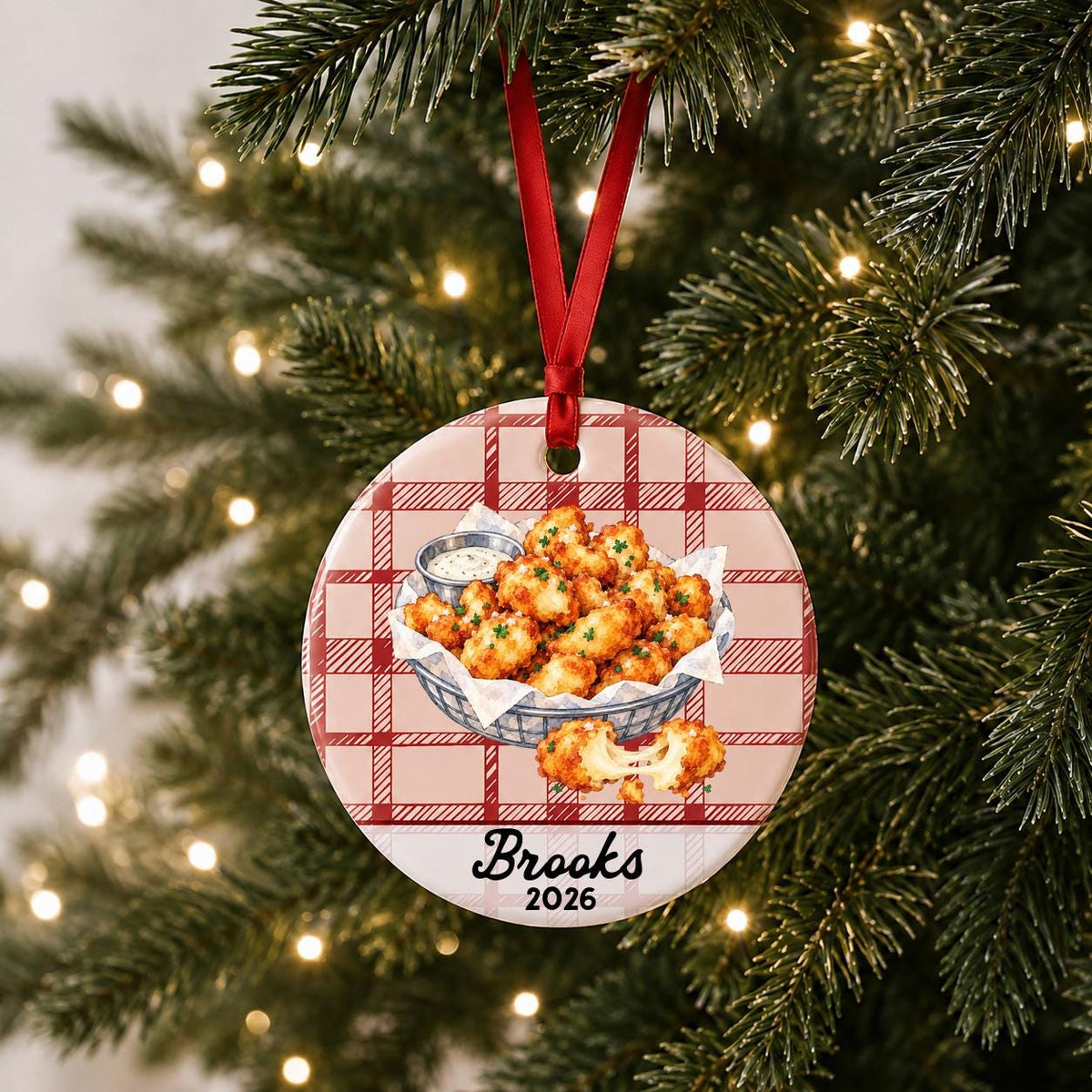 Personalized cheese curds ceramic ornament with name and year on red plaid hanging on a lit Christmas tree