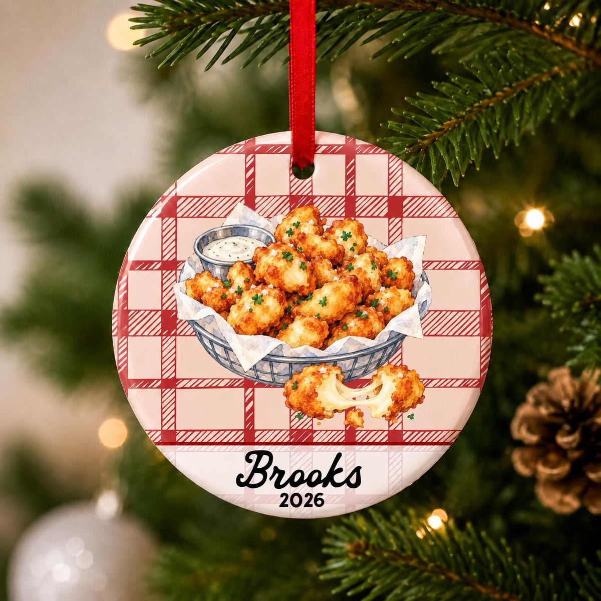 Close-up of the personalized cheese curds ceramic ornament with name and year on red plaid hanging on a Christmas tree