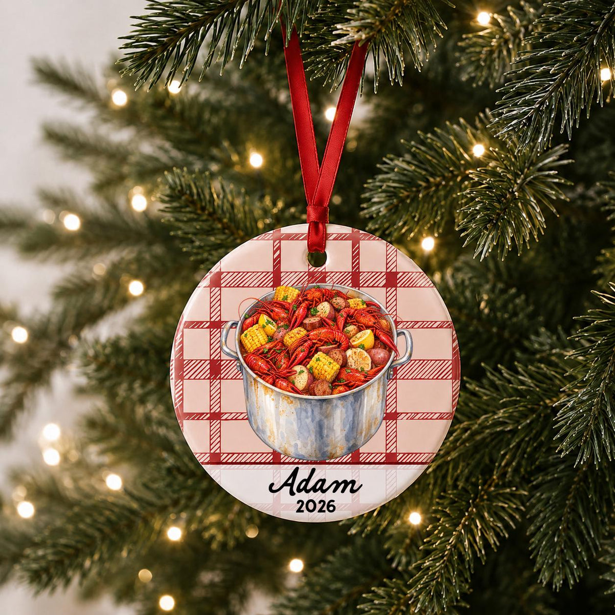 Personalized crawfish boil ceramic ornament with name and year on red plaid hanging on a lit Christmas tree