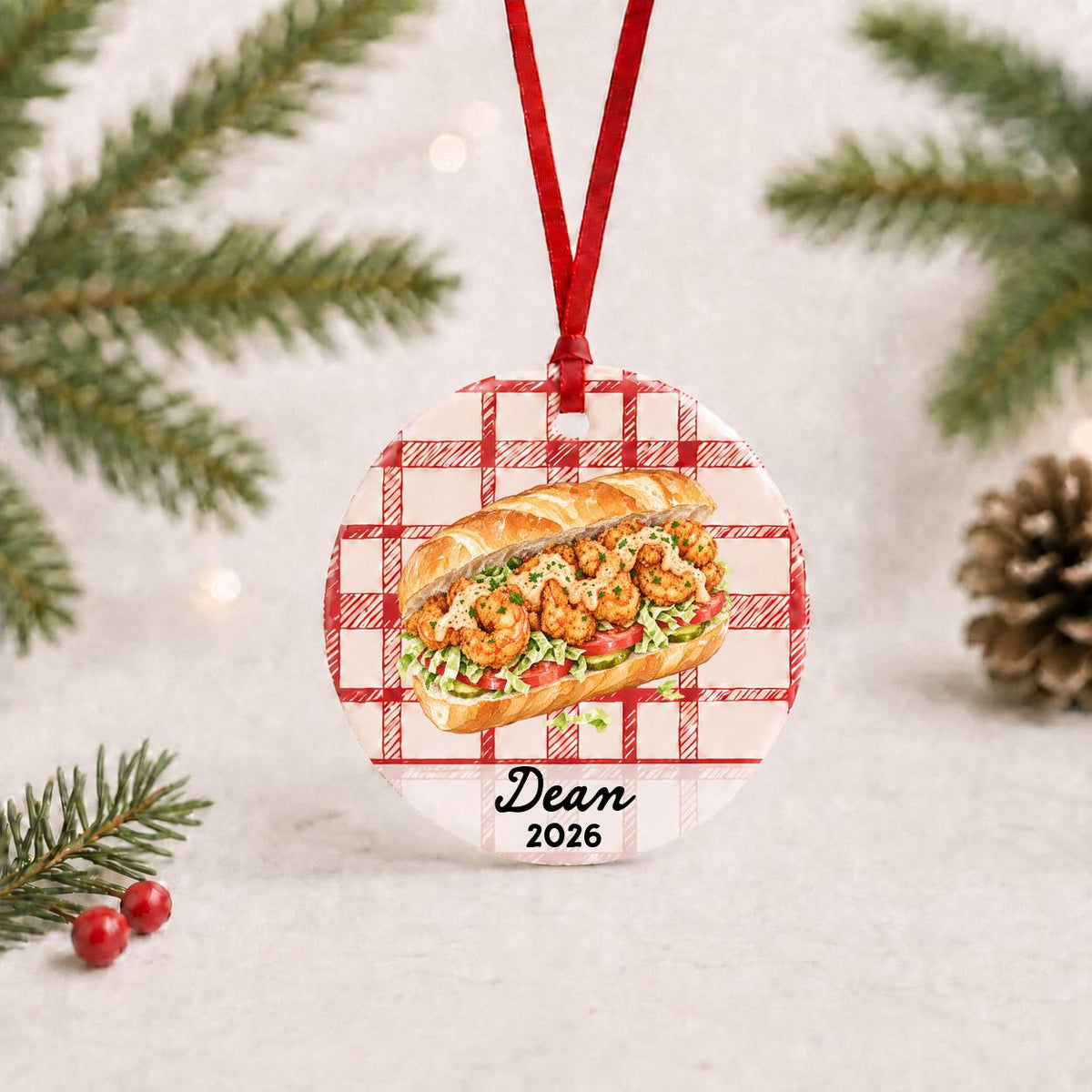 Personalized shrimp po' boy ceramic ornament with name and year on red plaid with red ribbon on a white surface with pine branches and pinecones