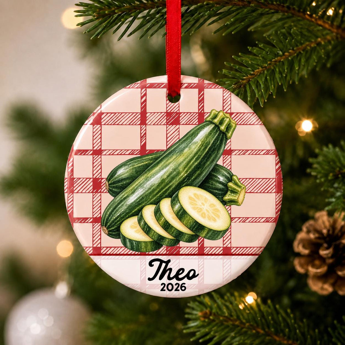 Close-up of the personalized zucchini ceramic ornament with name and year on red plaid hanging on a Christmas tree
