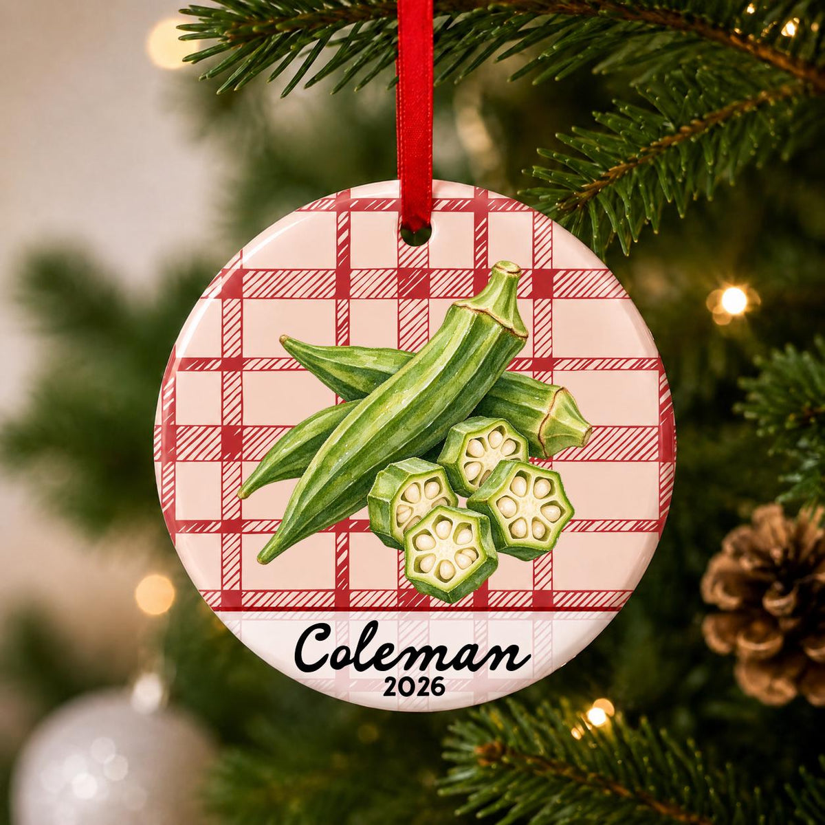 Close-up of the personalized okra ceramic ornament with name and year on red plaid hanging on a Christmas tree