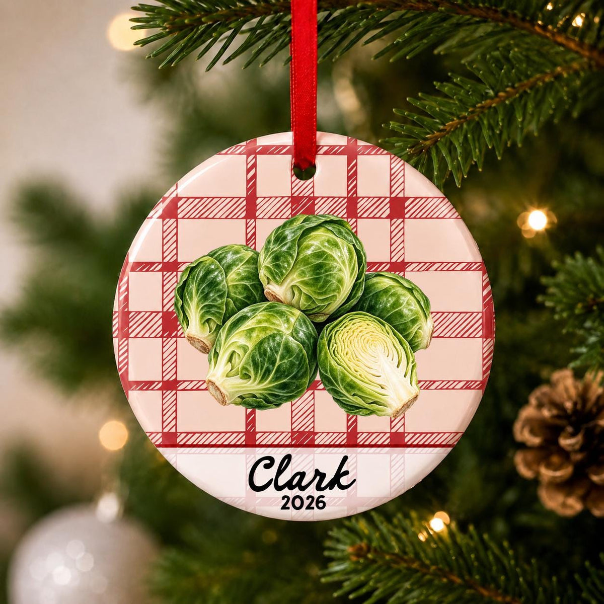 Close-up of the personalized brussels sprouts ceramic ornament with name and year on red plaid hanging on a Christmas tree