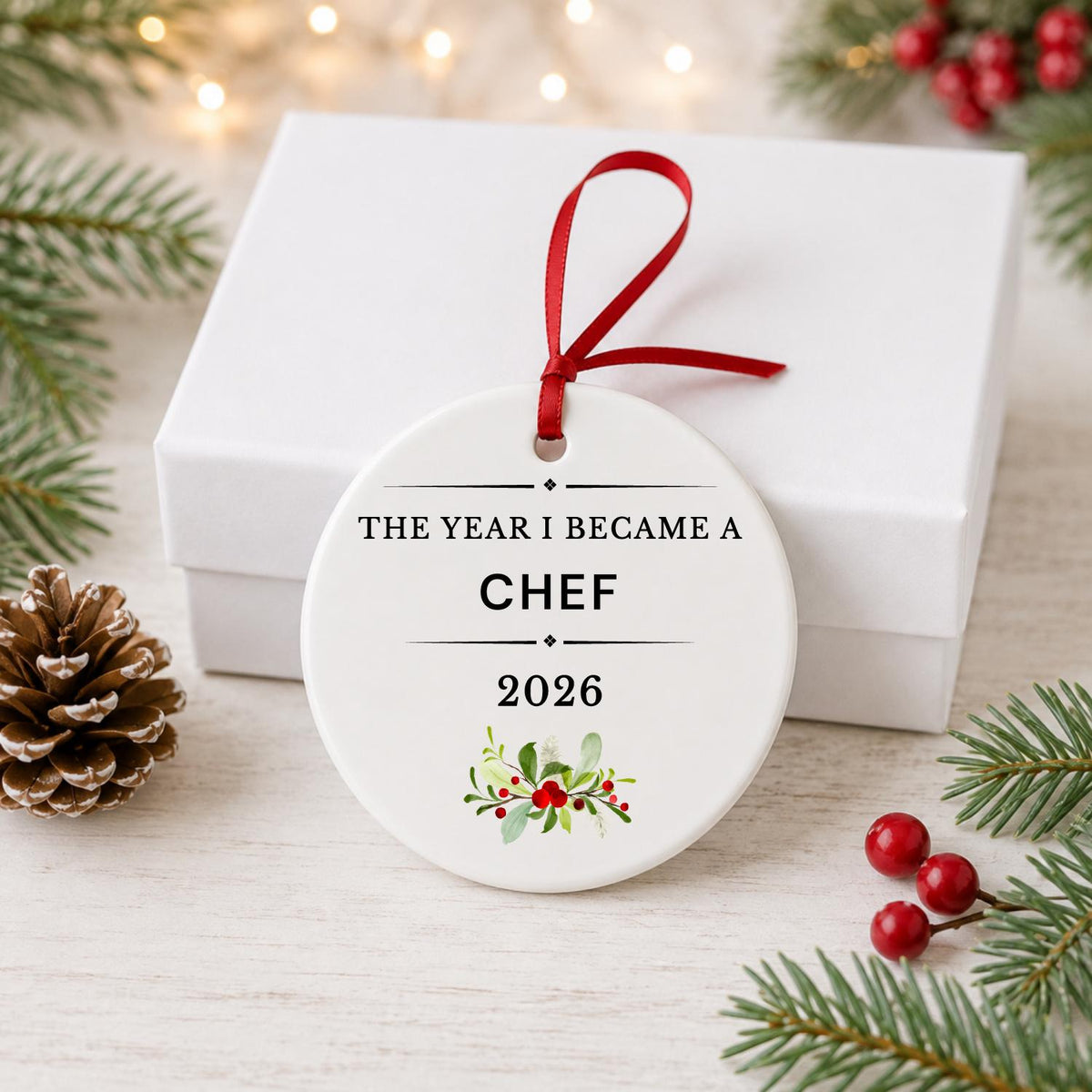 Chef 2026 ceramic ornament reading The Year I Became a Chef in front of a white gift box with pinecones and red berries