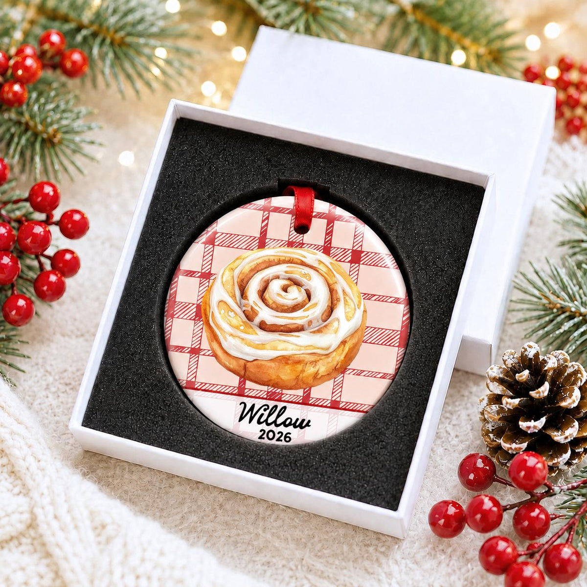 Personalized cinnamon roll ceramic ornament with name and year on red plaid in a white gift box with protective foam