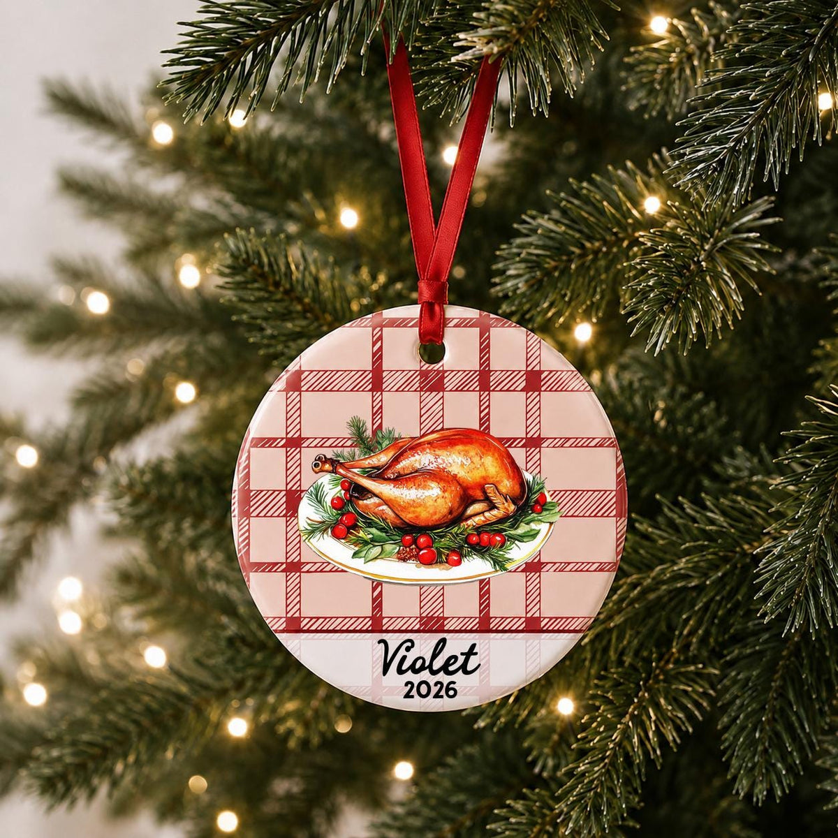 Personalized roast turkey ceramic ornament with name and year on red plaid hanging on a lit Christmas tree