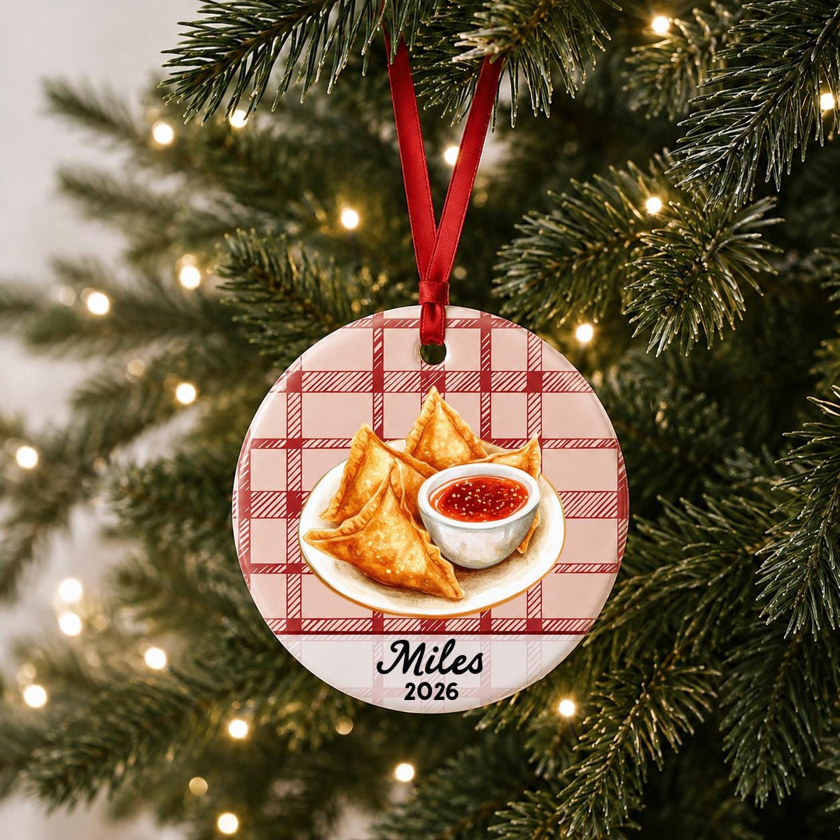Personalized crab rangoon ceramic ornament with name and year on red plaid hanging on a lit Christmas tree