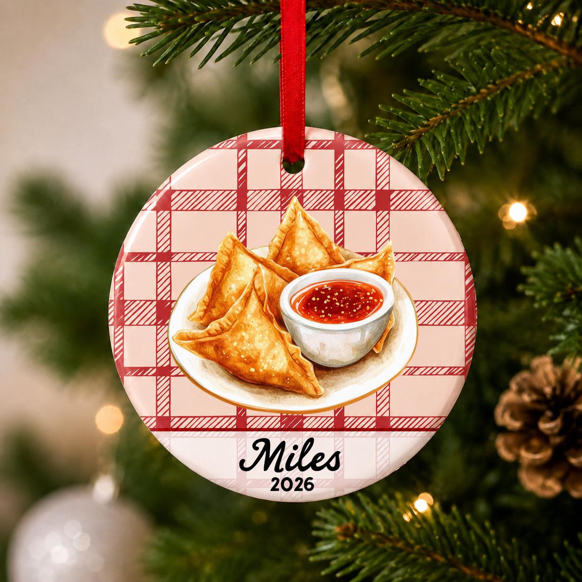 Close-up of the personalized crab rangoon ceramic ornament with name and year on red plaid hanging on a Christmas tree