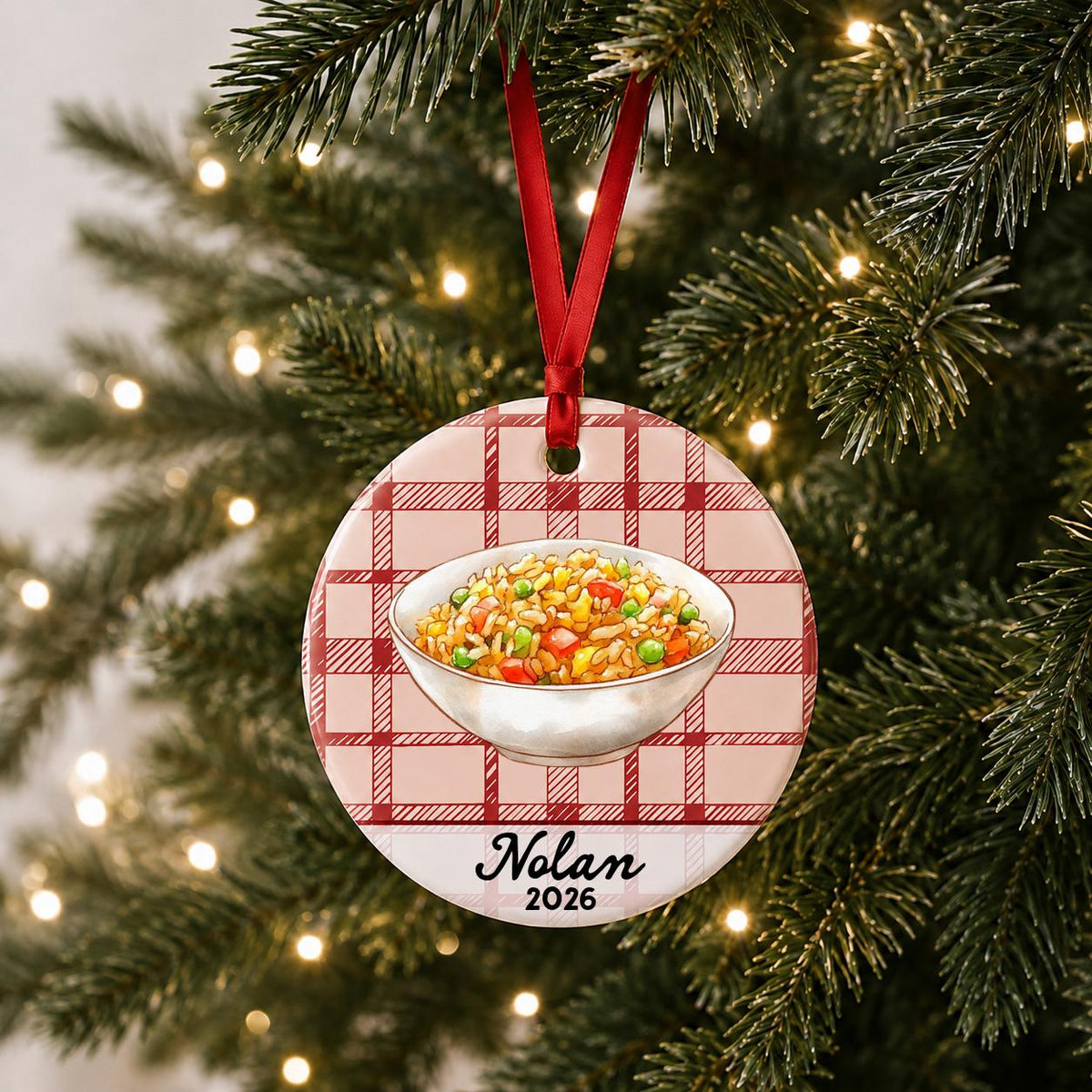 Personalized fried rice ceramic ornament with name and year on red plaid hanging on a lit Christmas tree