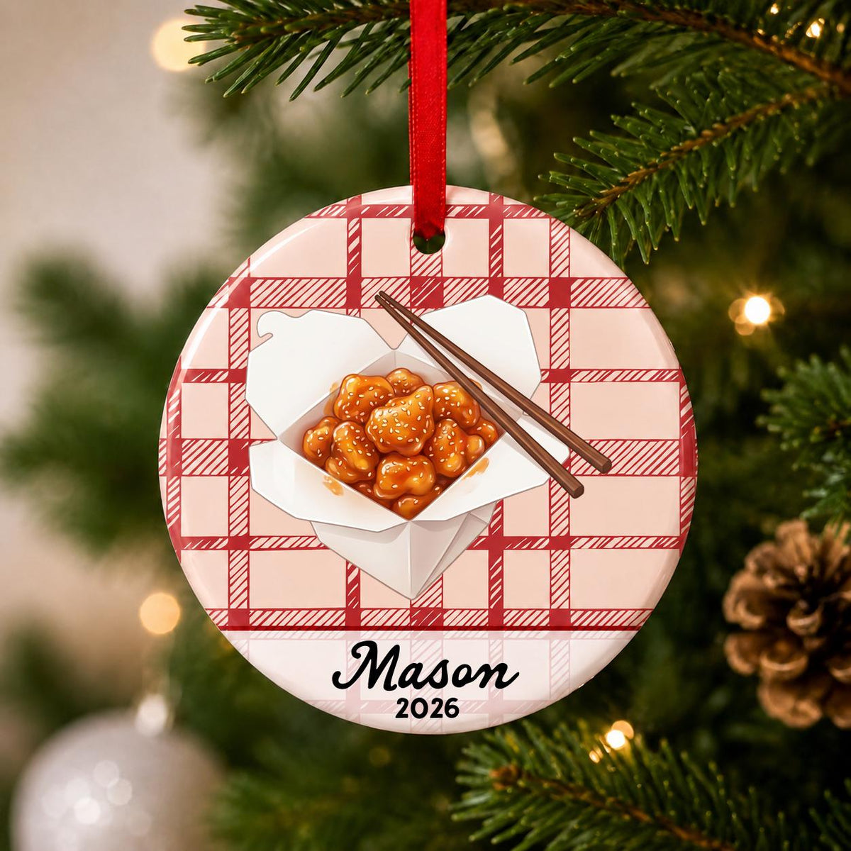 Close-up of the personalized sesame chicken ceramic ornament with name and year on red plaid hanging on a Christmas tree