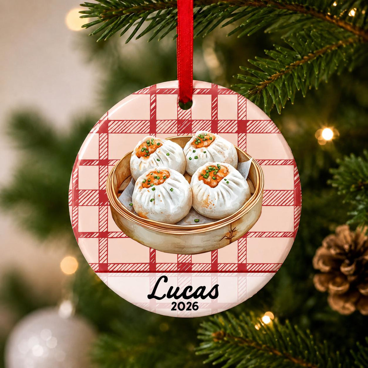 Close-up of the personalized shumai ceramic ornament with name and year on red plaid hanging on a Christmas tree