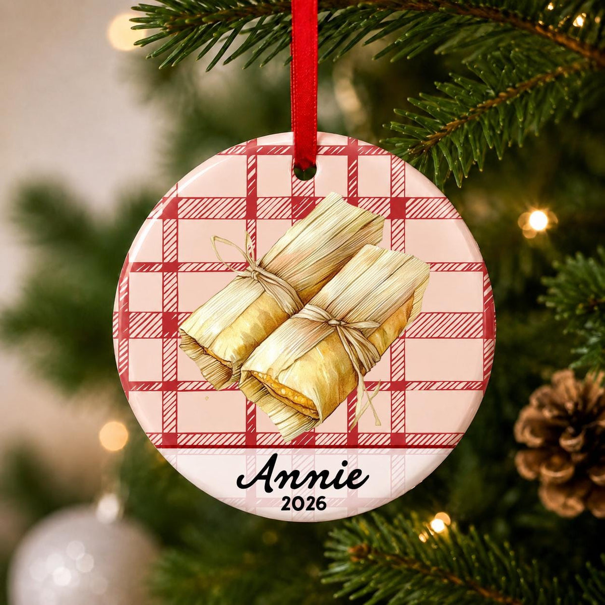 Close-up of the personalized tamale ceramic ornament with name and year on red plaid hanging on a Christmas tree