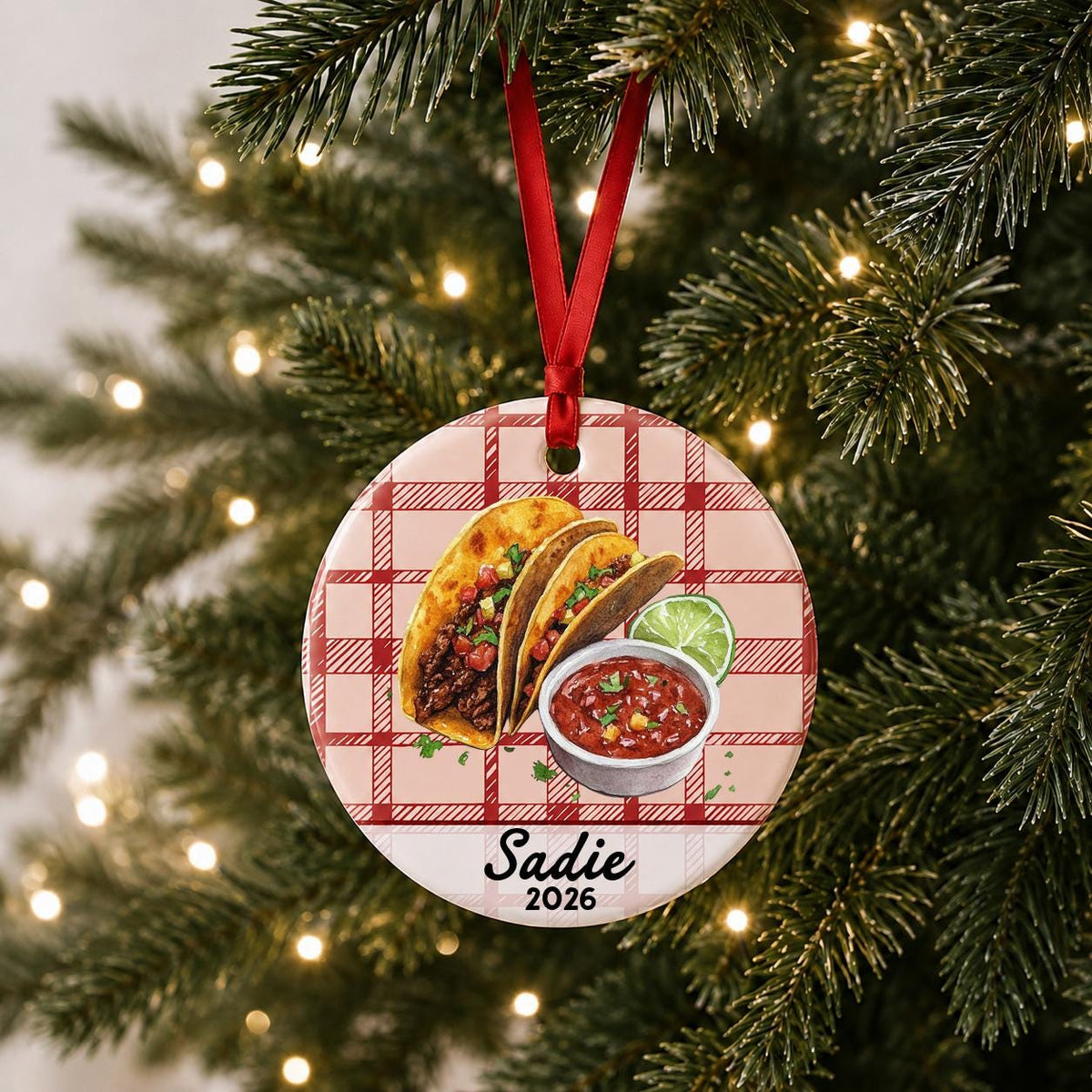 Personalized taco ceramic ornament with name and year on red plaid hanging on a lit Christmas tree