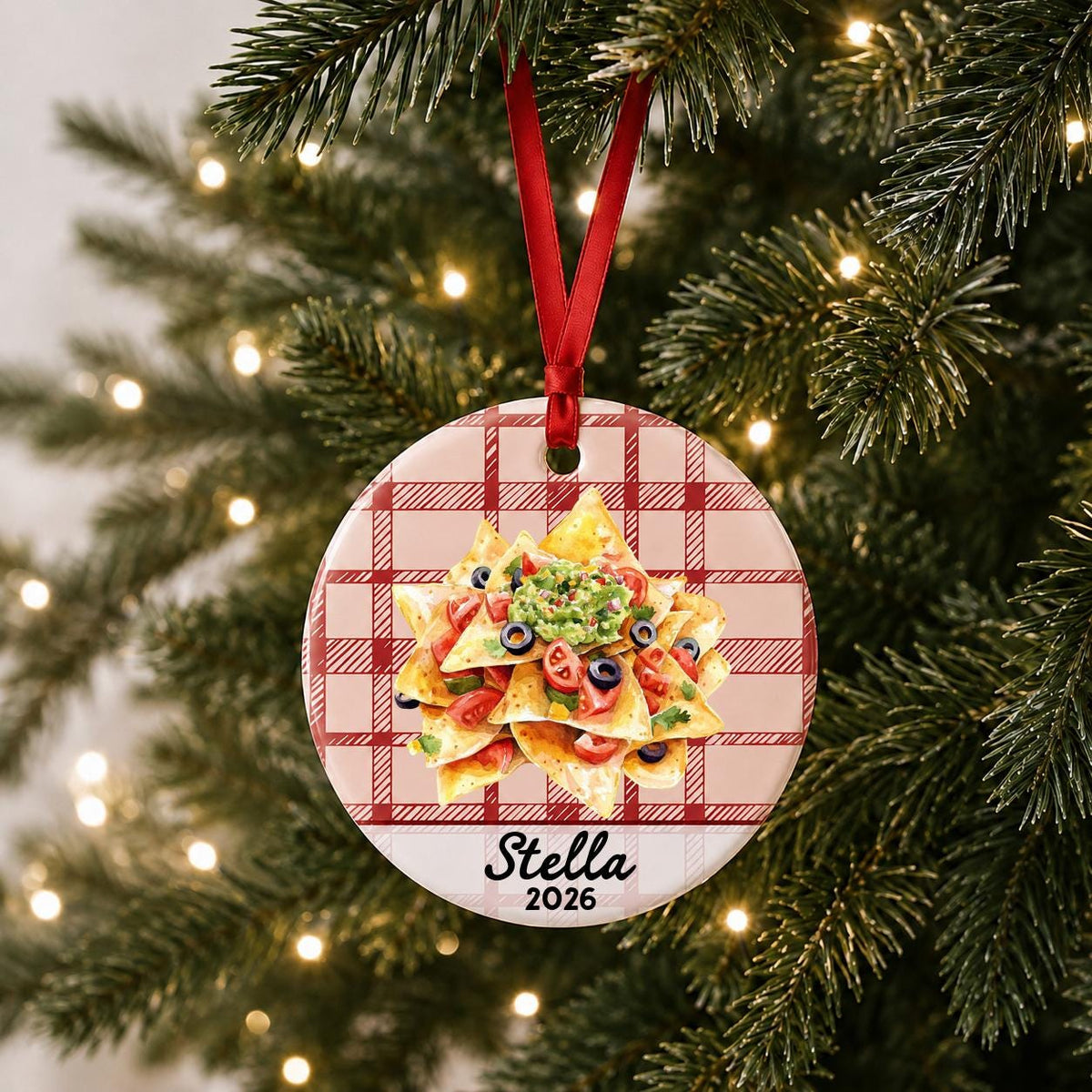 Personalized nachos ceramic ornament with name and year on red plaid hanging on a lit Christmas tree