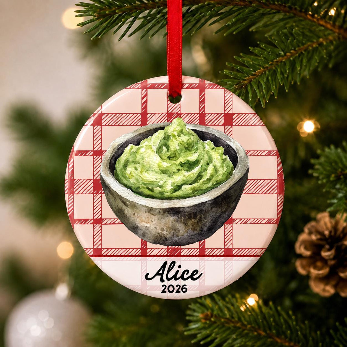Close-up of the personalized guacamole ceramic ornament with name and year on red plaid hanging on a Christmas tree