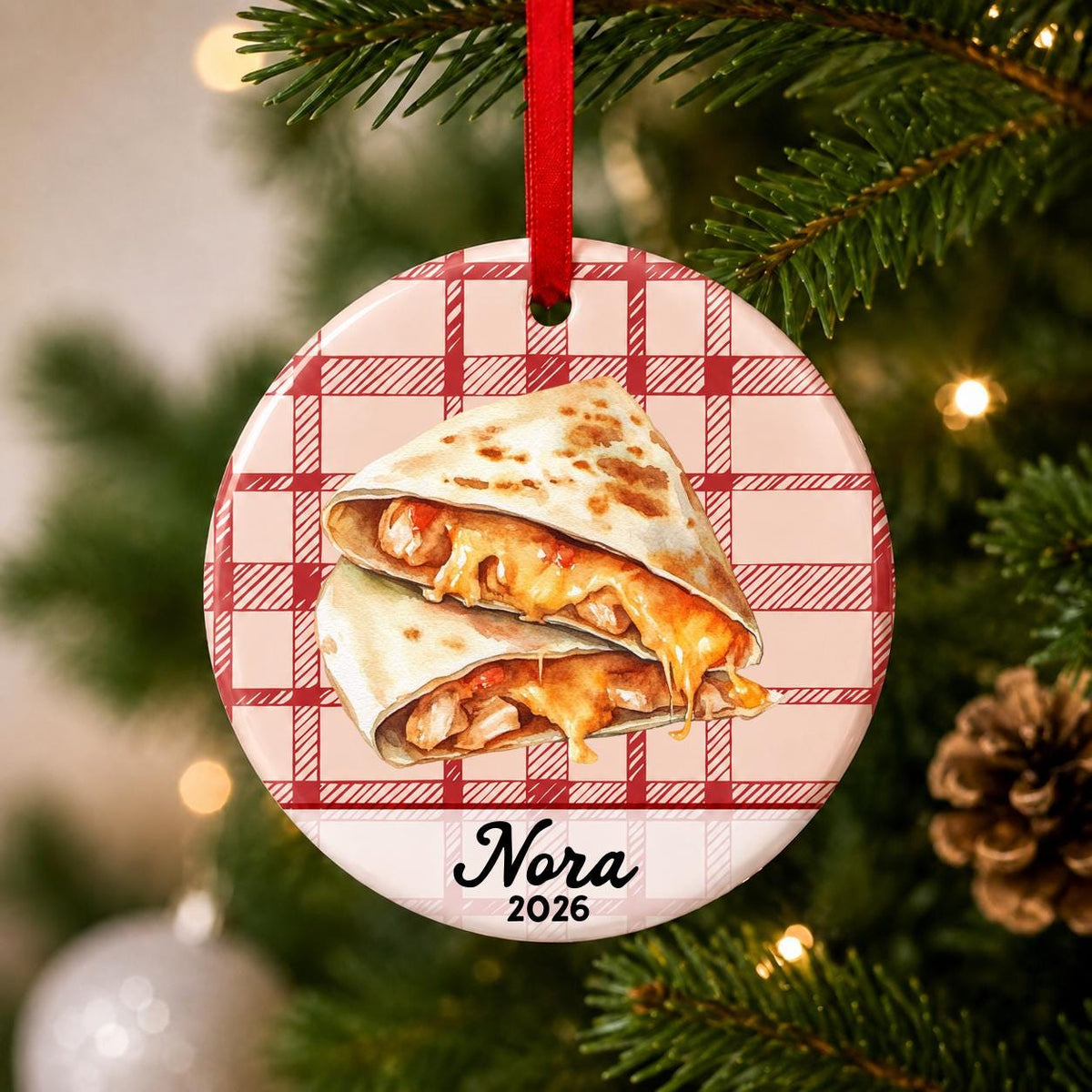 Close-up of the personalized quesadilla ceramic ornament with name and year on red plaid hanging on a Christmas tree