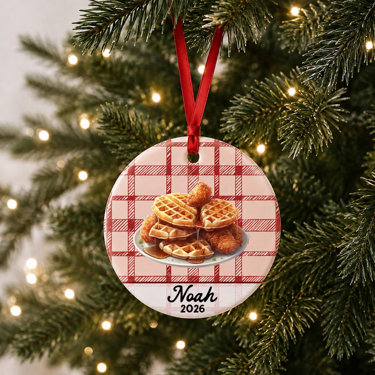Personalized chicken and waffles ceramic ornament with name and year on red plaid hanging on a lit Christmas tree