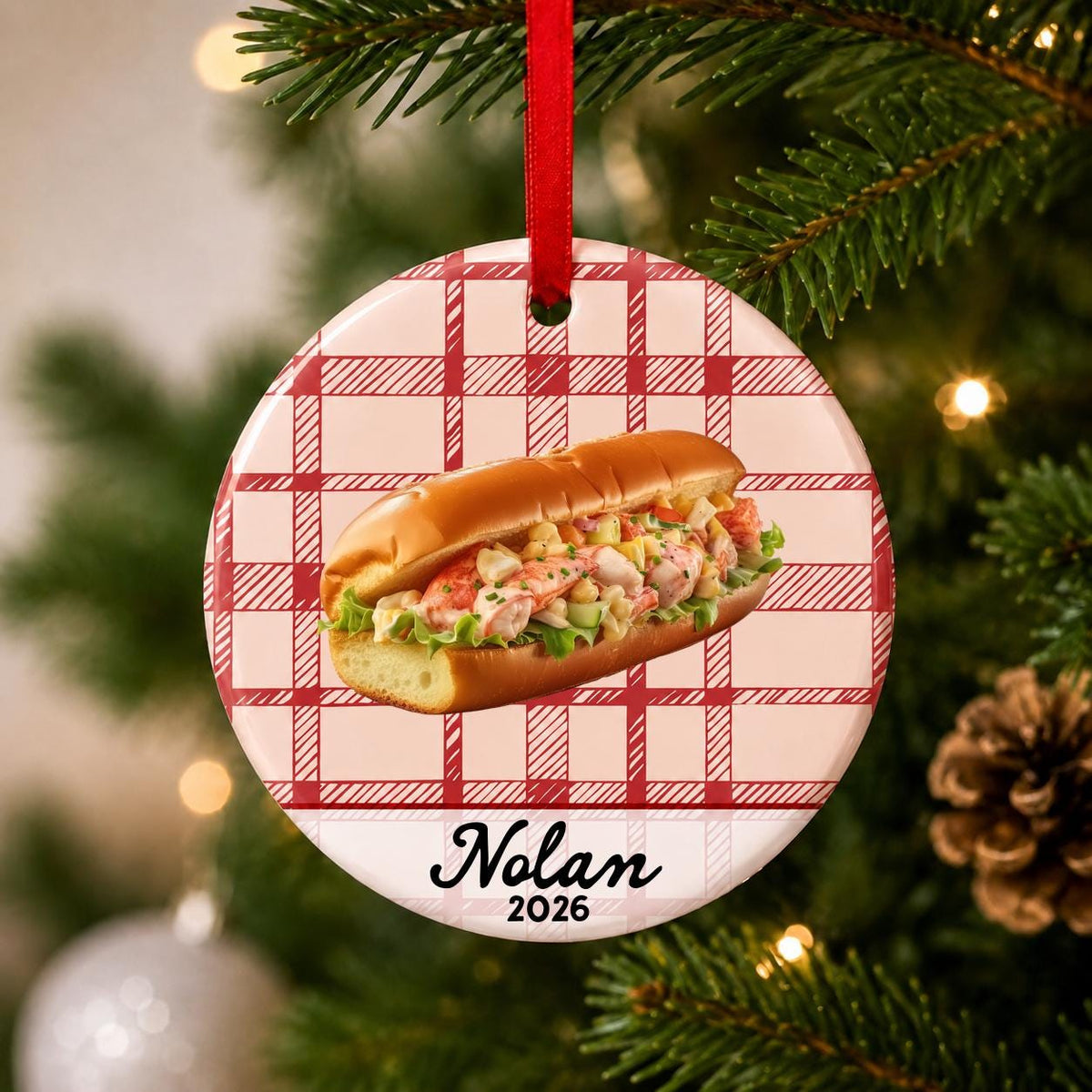 Close-up of the personalized lobster roll ceramic ornament with name and year on red plaid hanging on a Christmas tree