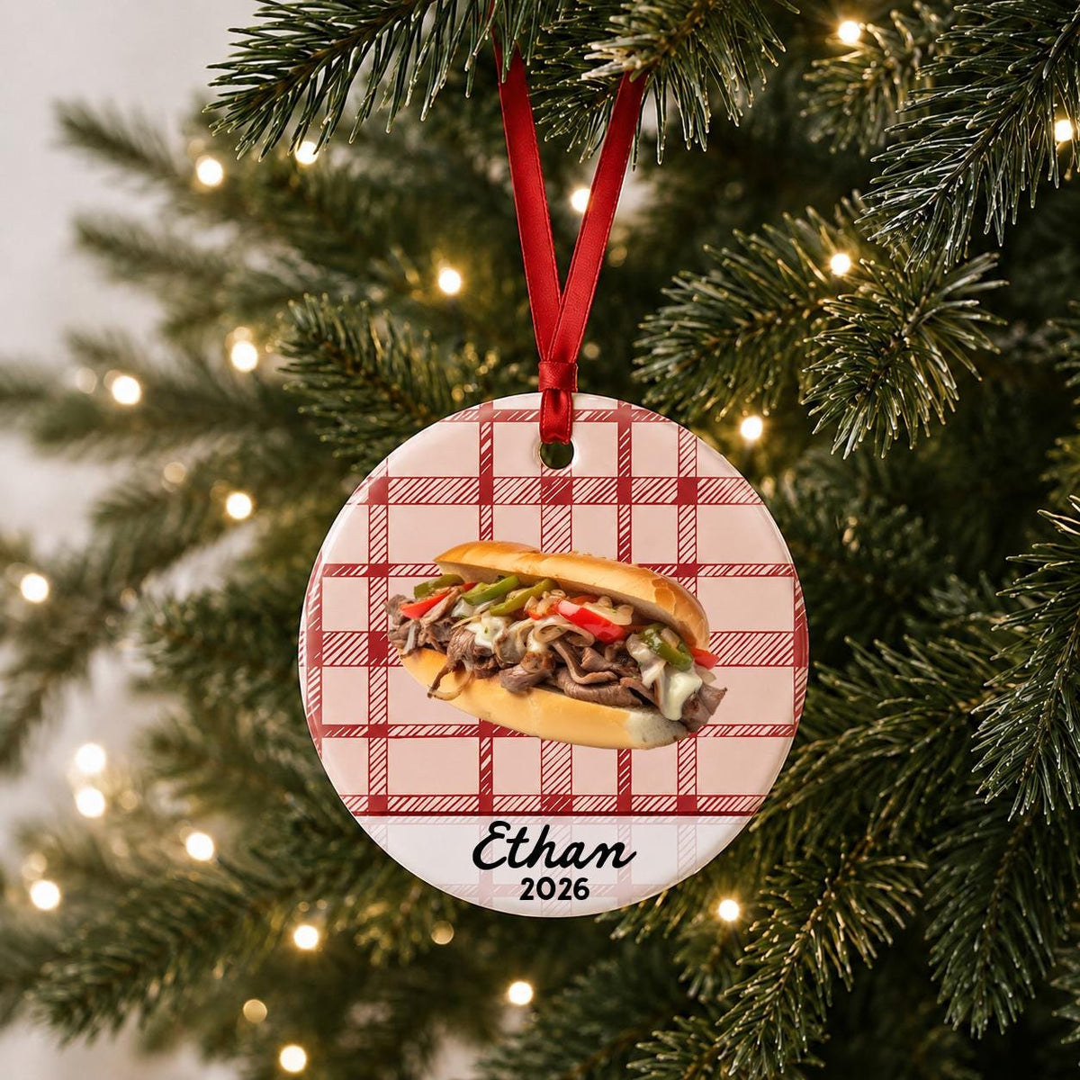 Personalized Philly cheesesteak ceramic ornament with name and year on red plaid hanging on a lit Christmas tree