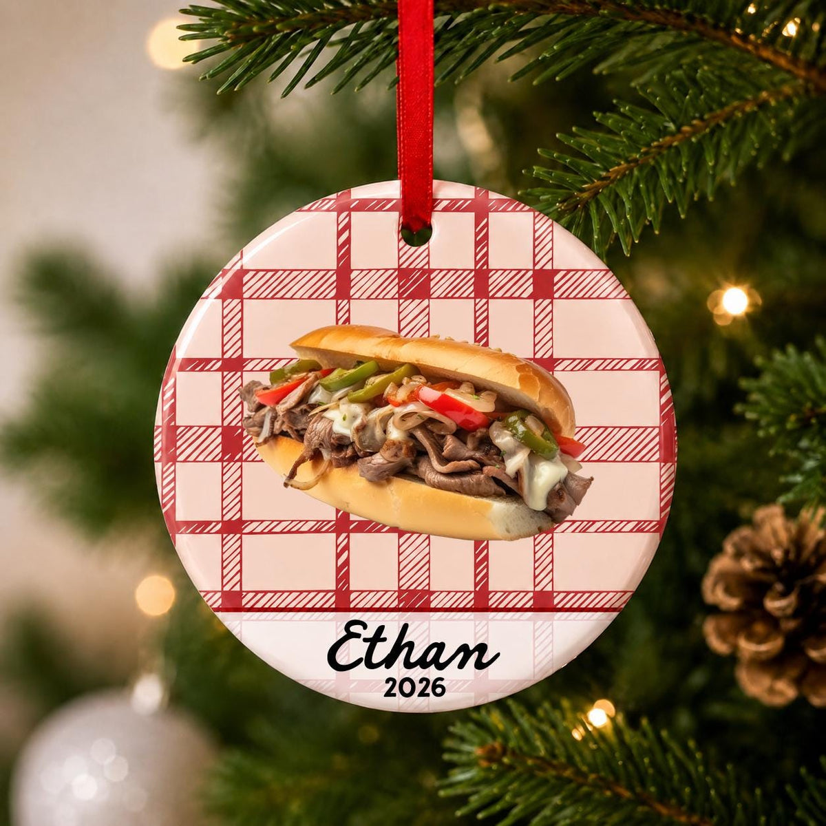 Close-up of the personalized Philly cheesesteak ceramic ornament with name and year on red plaid hanging on a Christmas tree