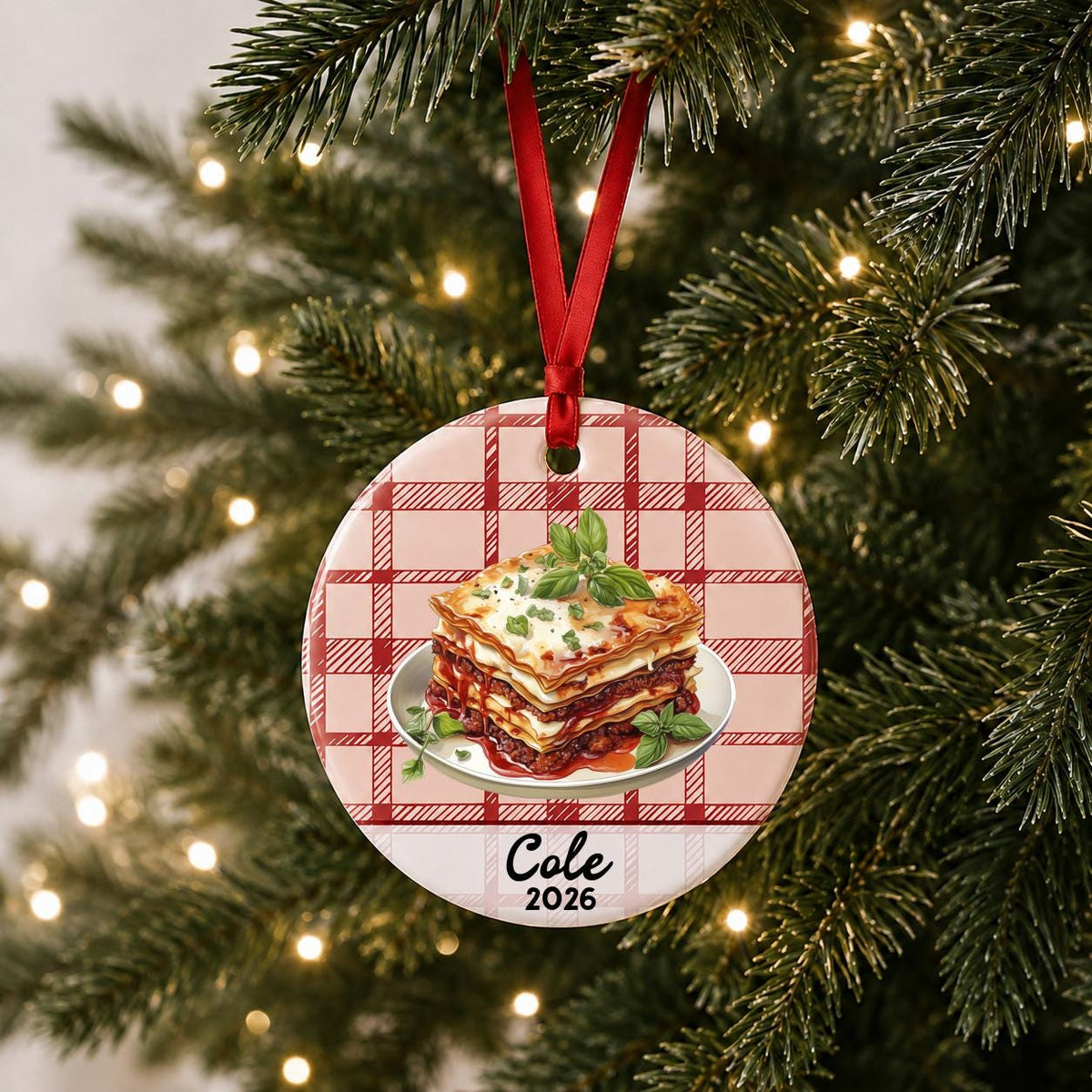 Personalized lasagna ceramic ornament with name and year on red plaid hanging on a lit Christmas tree