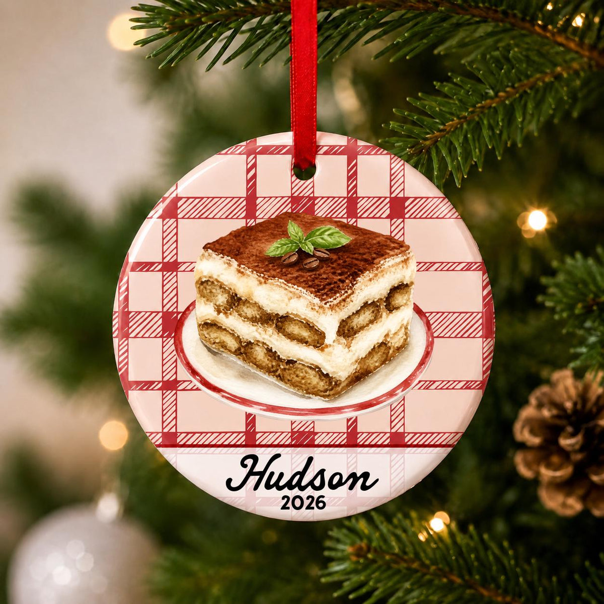 Close-up of the personalized tiramisu ceramic ornament with name and year on red plaid hanging on a Christmas tree