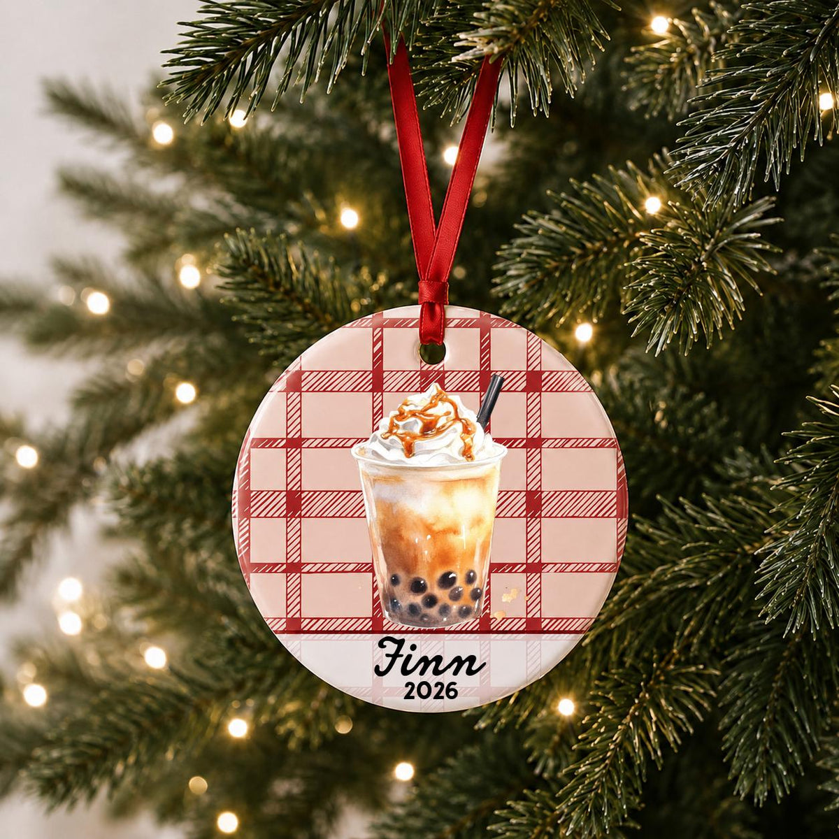 Personalized brown sugar boba ceramic ornament with name and year on red plaid hanging on a lit Christmas tree