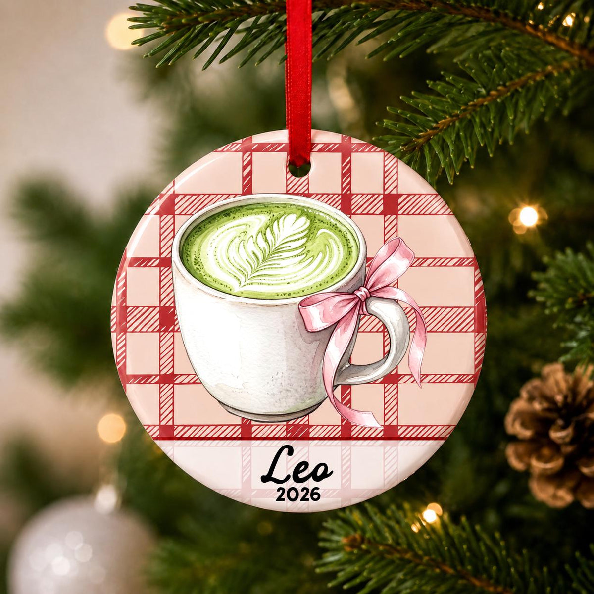 Close-up of the personalized matcha latte ceramic ornament with name and year on red plaid hanging on a Christmas tree
