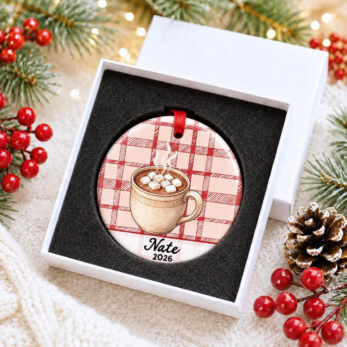 Personalized hot chocolate ceramic ornament with name and year on red plaid in a white gift box with protective foam