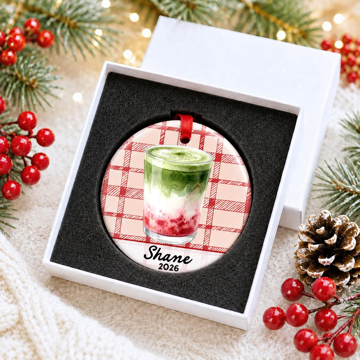 Personalized strawberry matcha latte ceramic ornament with name and year on red plaid in a white gift box with protective foam
