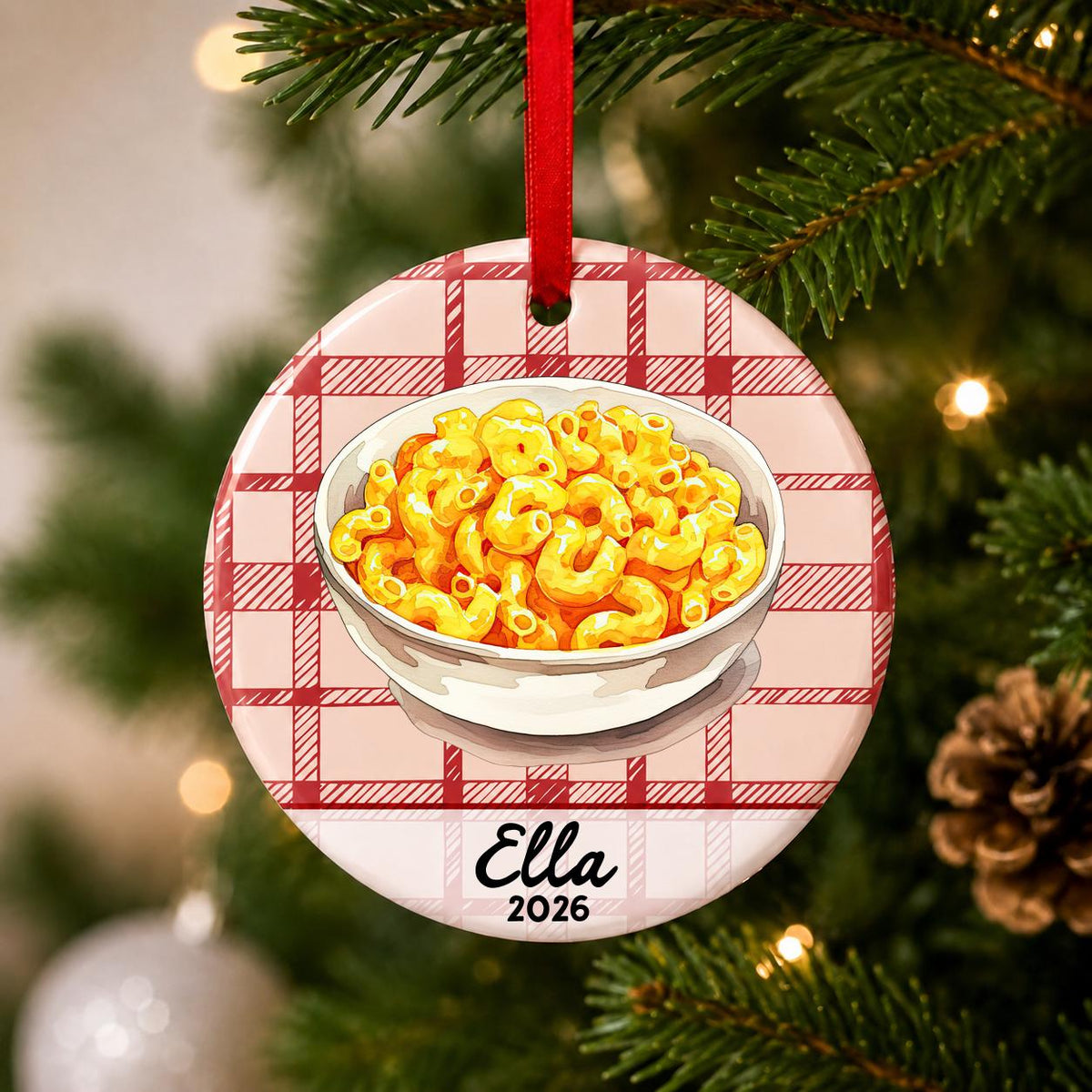 Close-up of the personalized mac and cheese ceramic ornament with name and year on red plaid hanging on a Christmas tree