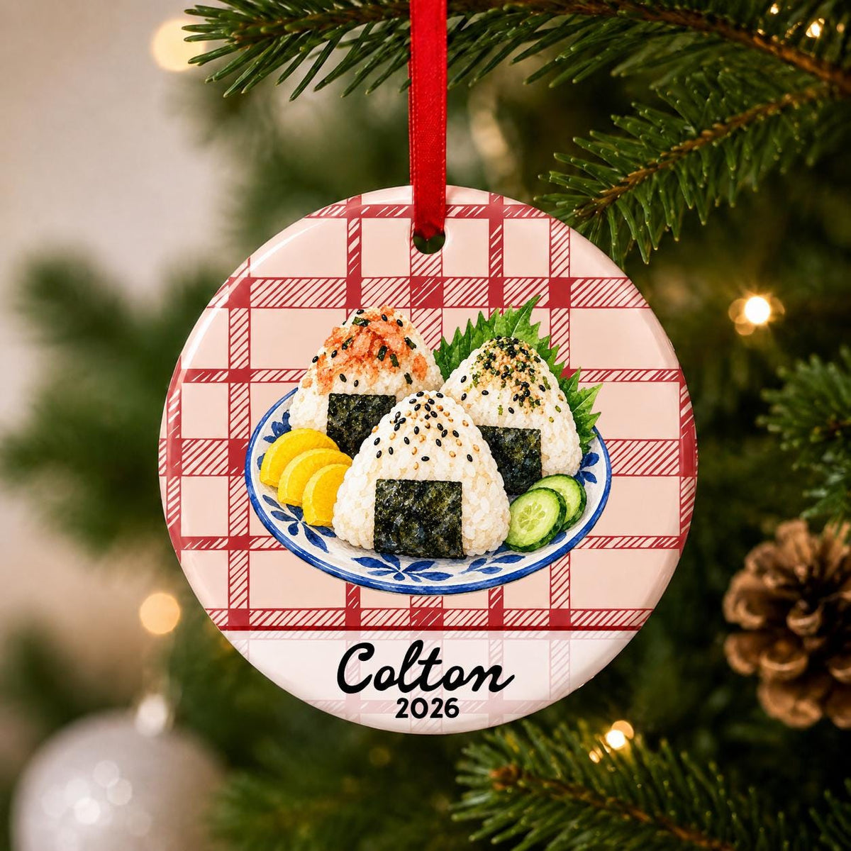 Close-up of the personalized onigiri ceramic ornament with name and year on red plaid hanging on a Christmas tree