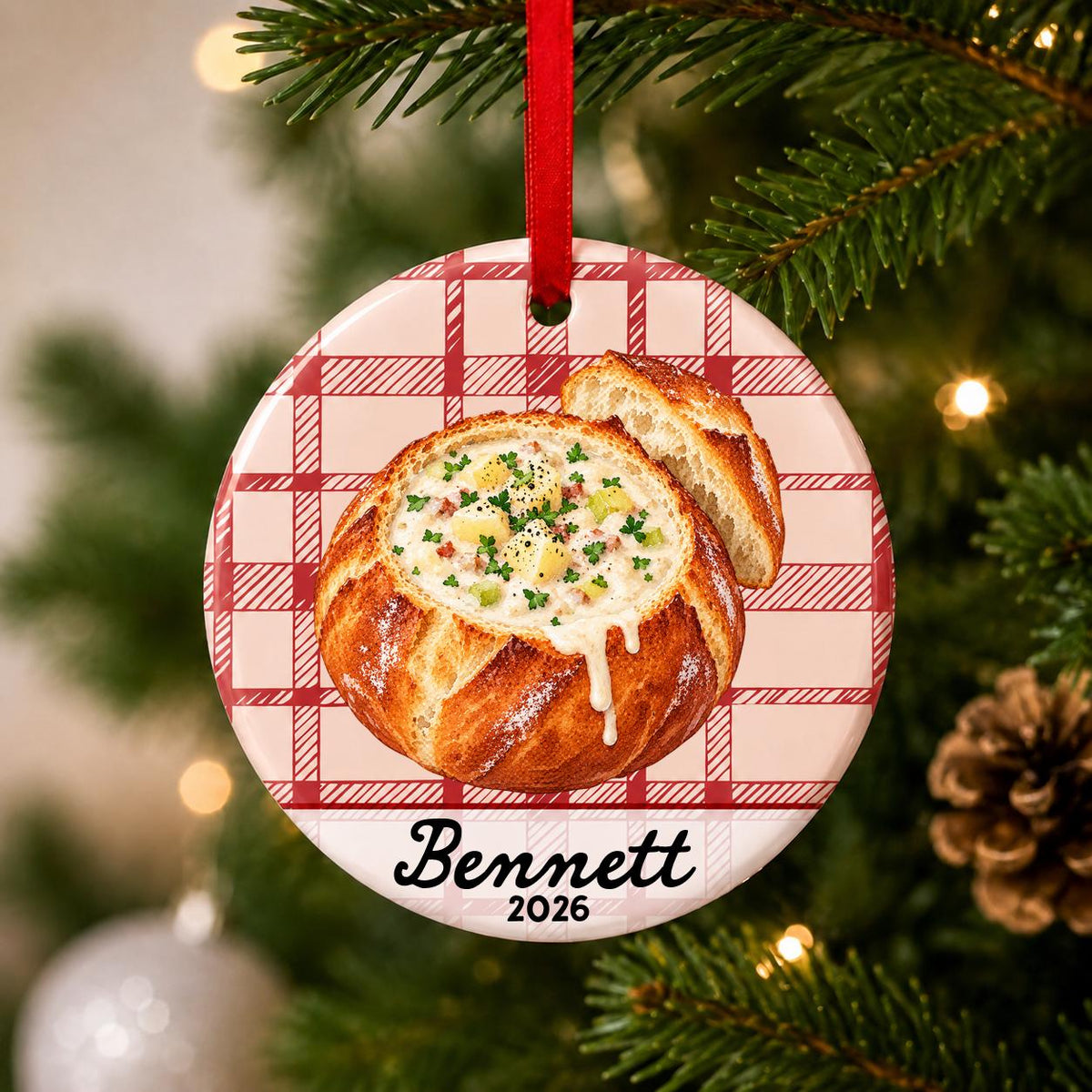 Close-up of the personalized clam chowder bread bowl ceramic ornament with name and year on red plaid hanging on a Christmas tree