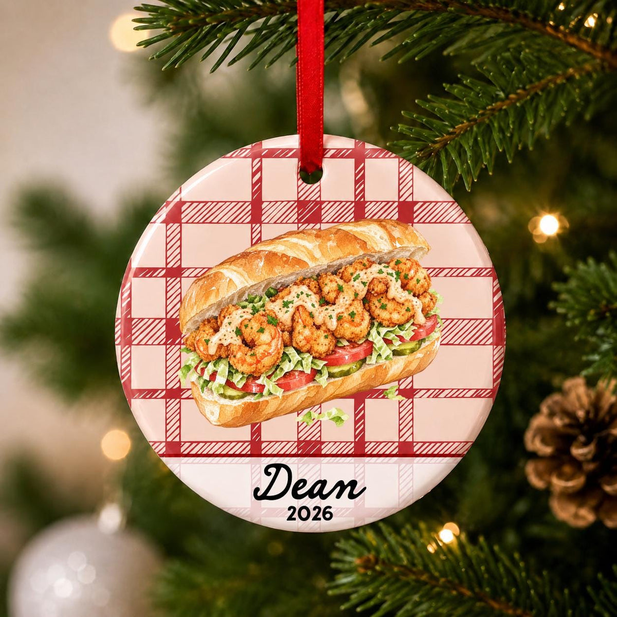Close-up of the personalized shrimp po' boy ceramic ornament with name and year on red plaid hanging on a Christmas tree