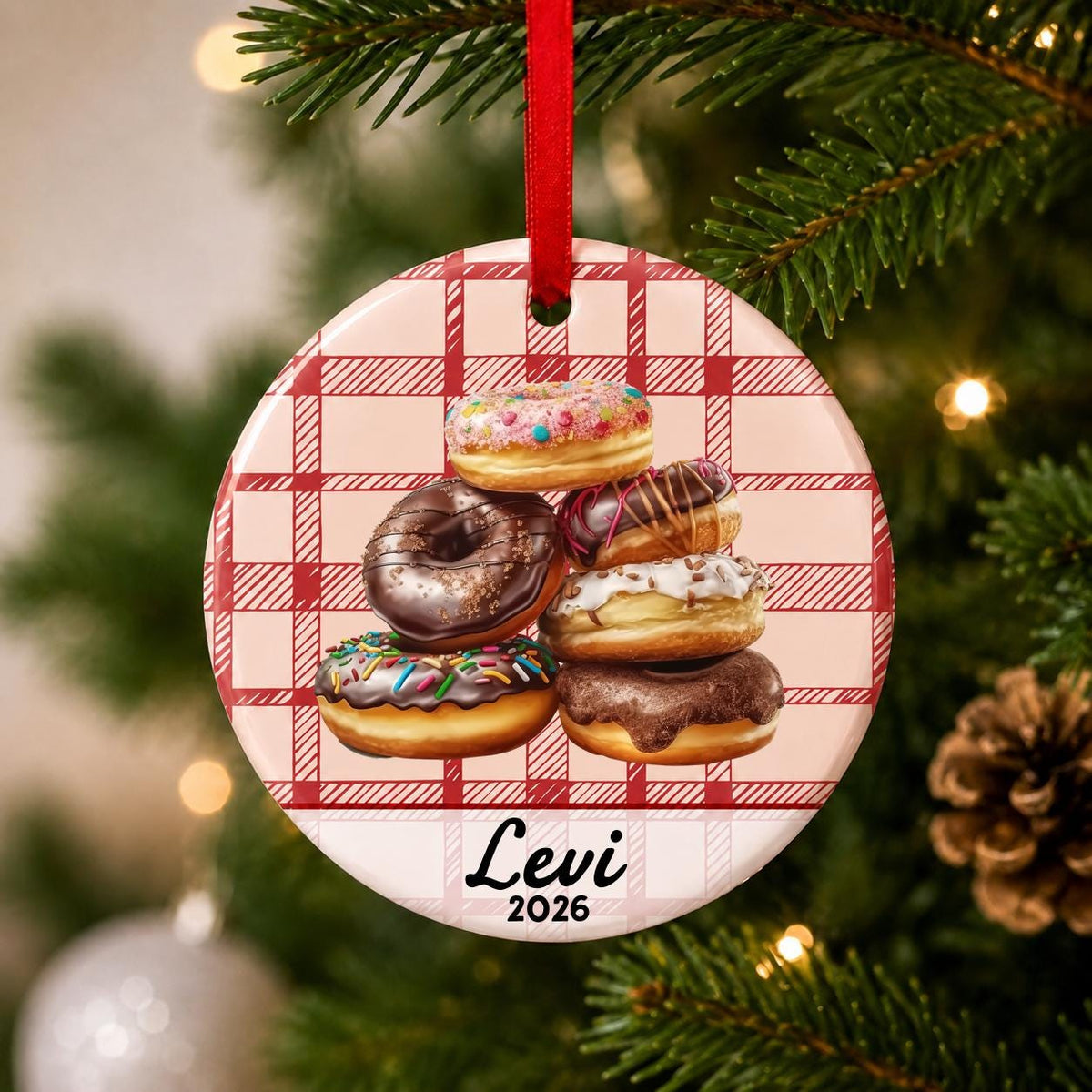 Close-up of the personalized donuts ceramic ornament with name and year on red plaid hanging on a Christmas tree