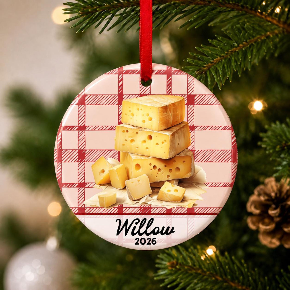 Close-up of the personalized Swiss cheese ceramic ornament with name and year on red plaid hanging on a Christmas tree