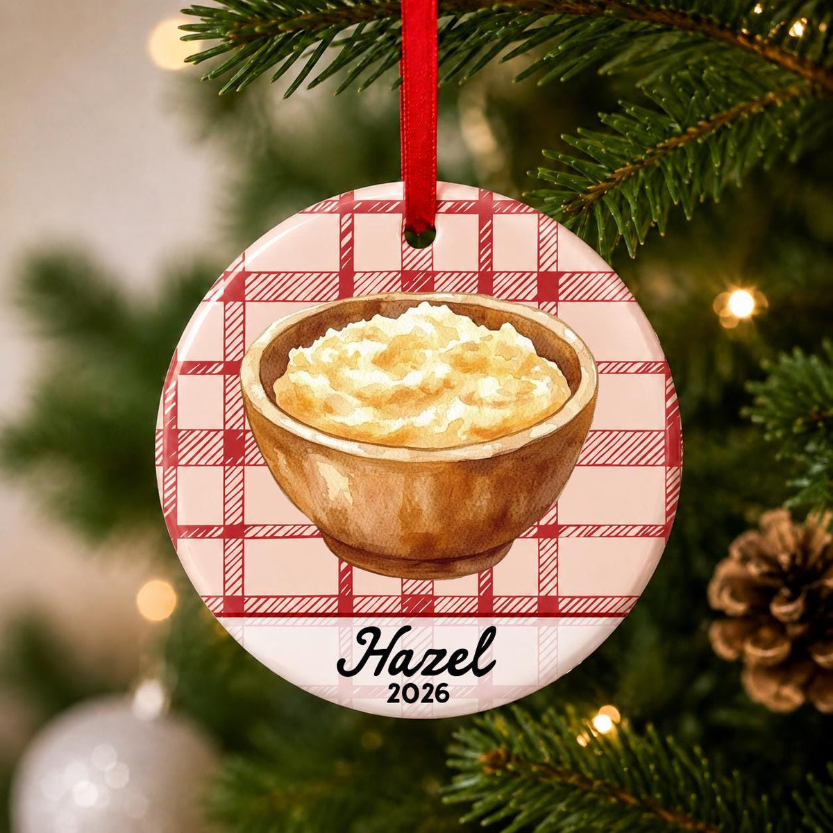 Close-up of the personalized mashed potatoes ceramic ornament with name and year on red plaid hanging on a Christmas tree